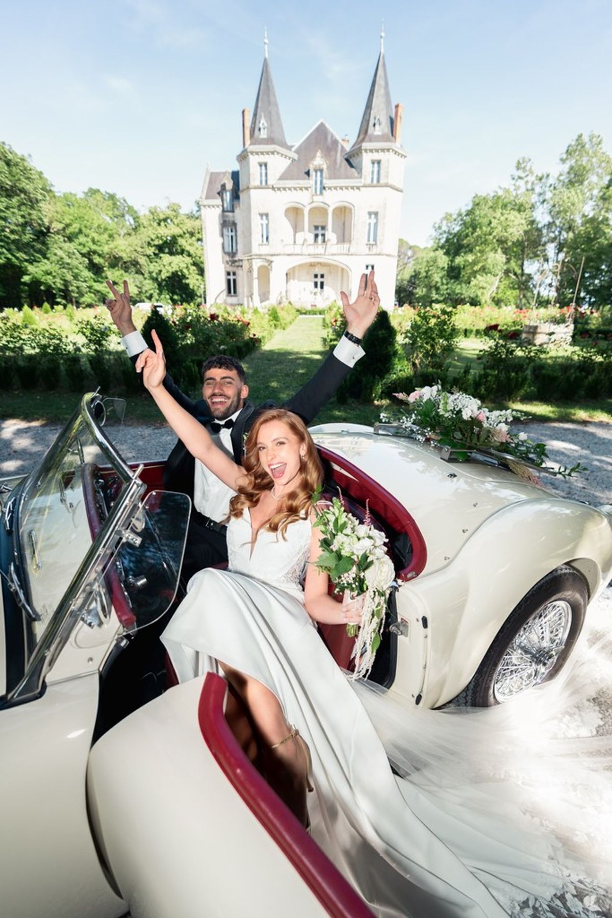 Blush and fuchsia styled shoot at Château du Causse, Occitanie, the couple celebrating in the vintage car in front of the château