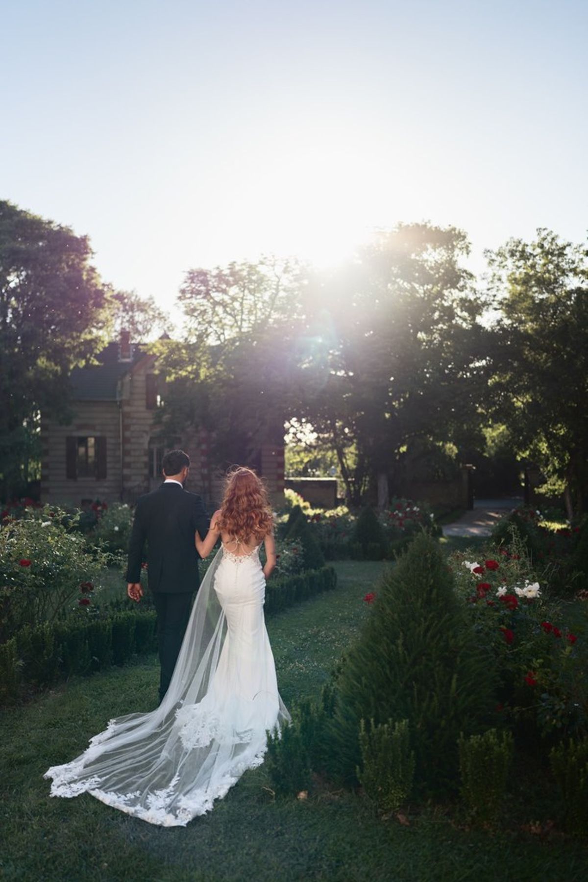 Blush and fuchsia styled shoot at Château du Causse, Occitanie, the couple walking through the garden in the evening sun