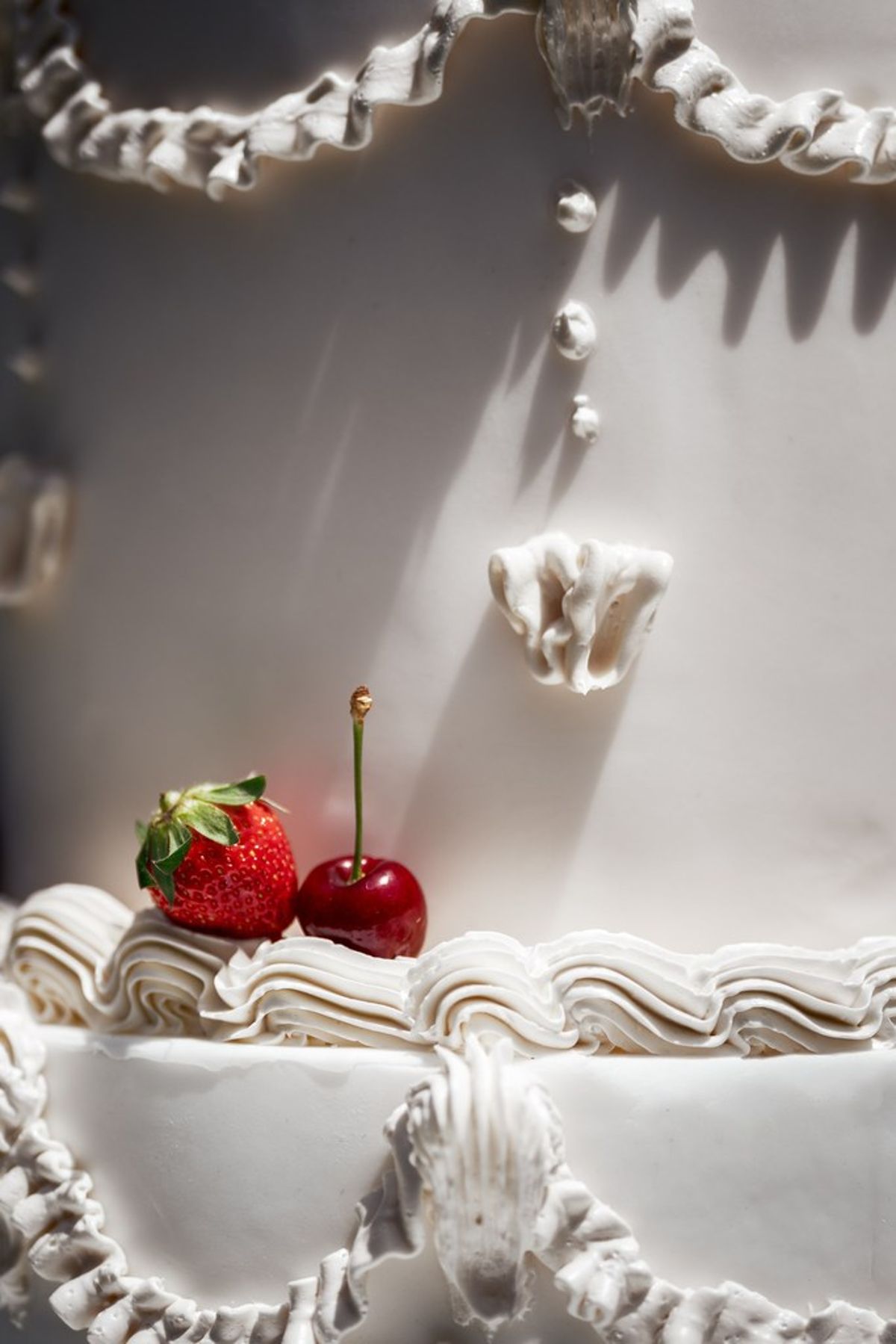Blush and fuchsia styled shoot at Château du Causse, Occitanie, piped cake detail with strawberries and cherries