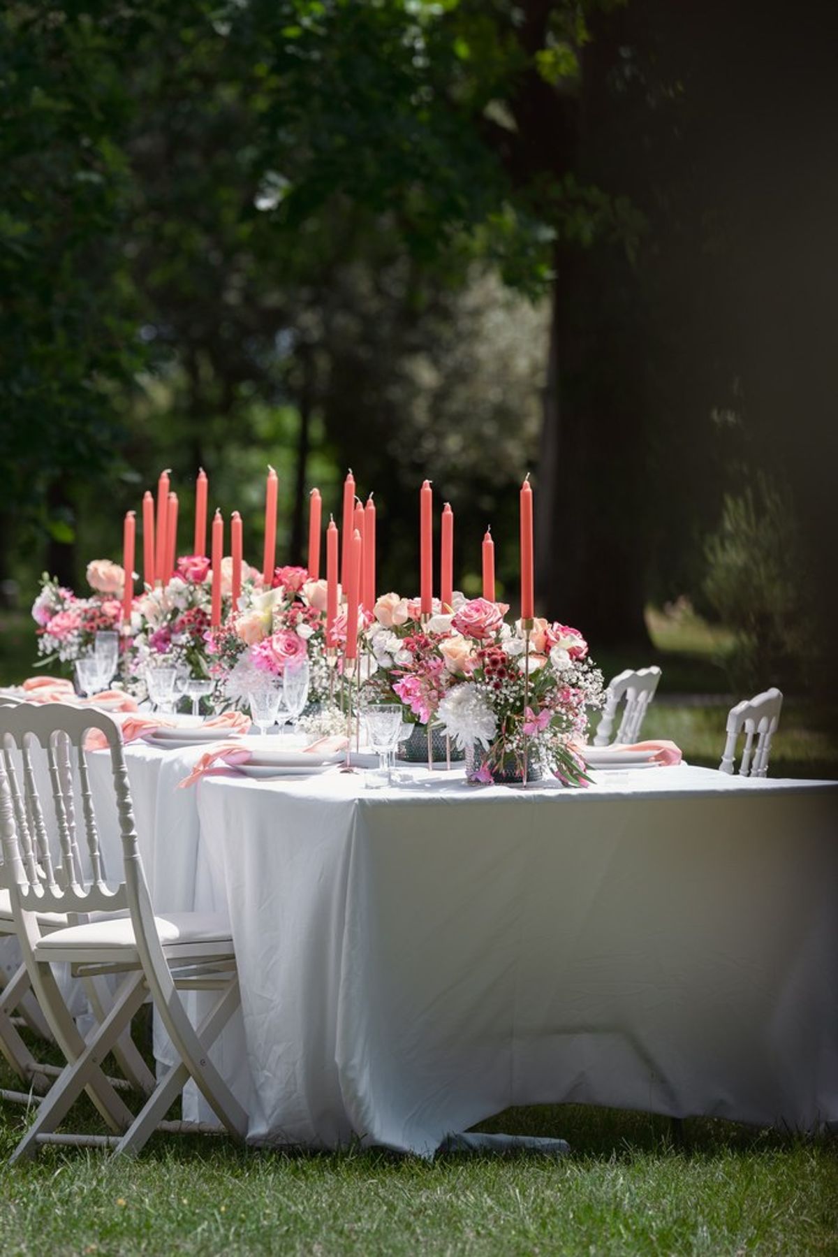 Blush and fuchsia styled shoot at Château du Causse, Occitanie, a long table with taper candles and raspberry and blush flowers