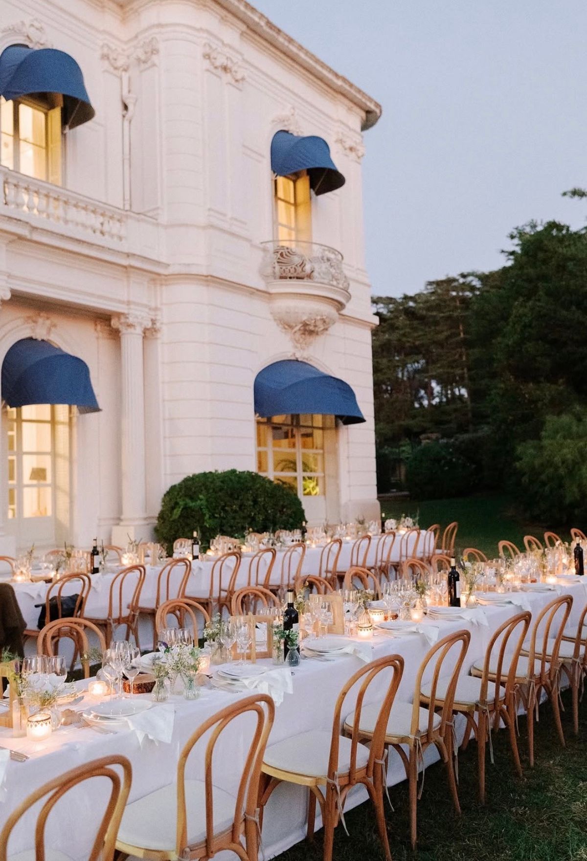 Long candlelit dinner tables set on the lawn beside the villa at Domaine Rocabella, French Riviera