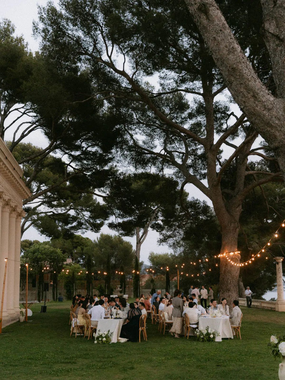 Guests dining under pine trees and string lights at Domaine Rocabella, French Riviera