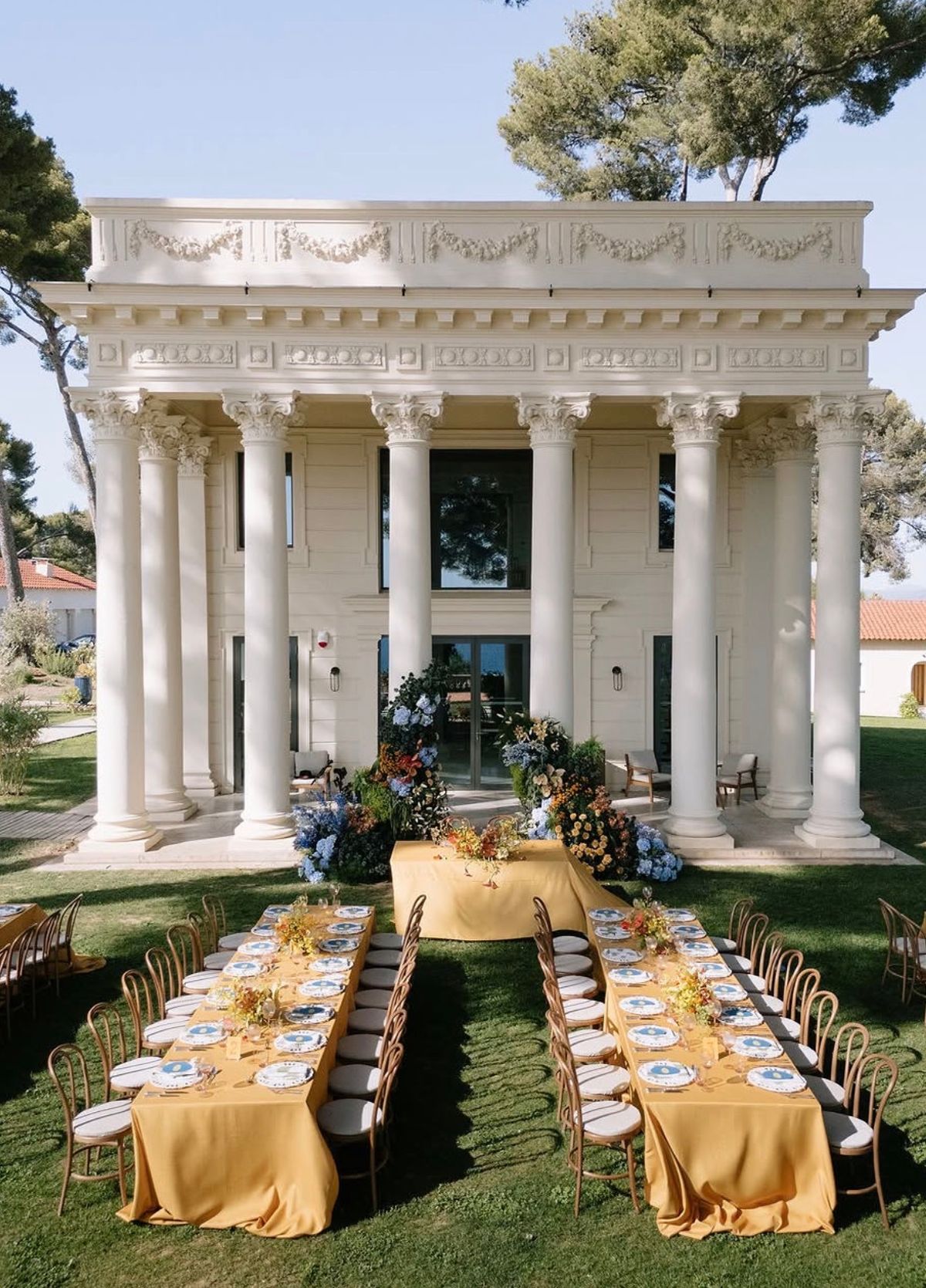 Long dinner tables with yellow linen set before the colonnaded pavilion at Domaine Rocabella, French Riviera