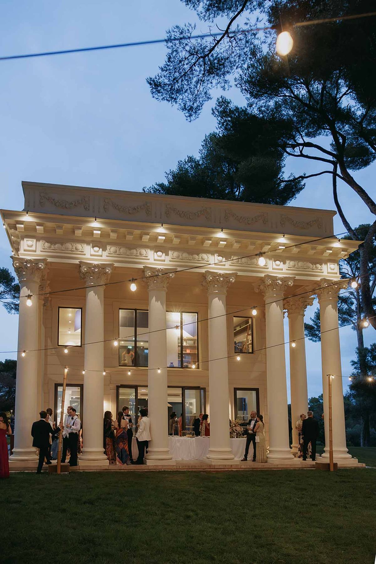 Guests gathered at dusk before the lit colonnaded pavilion at Domaine Rocabella, French Riviera