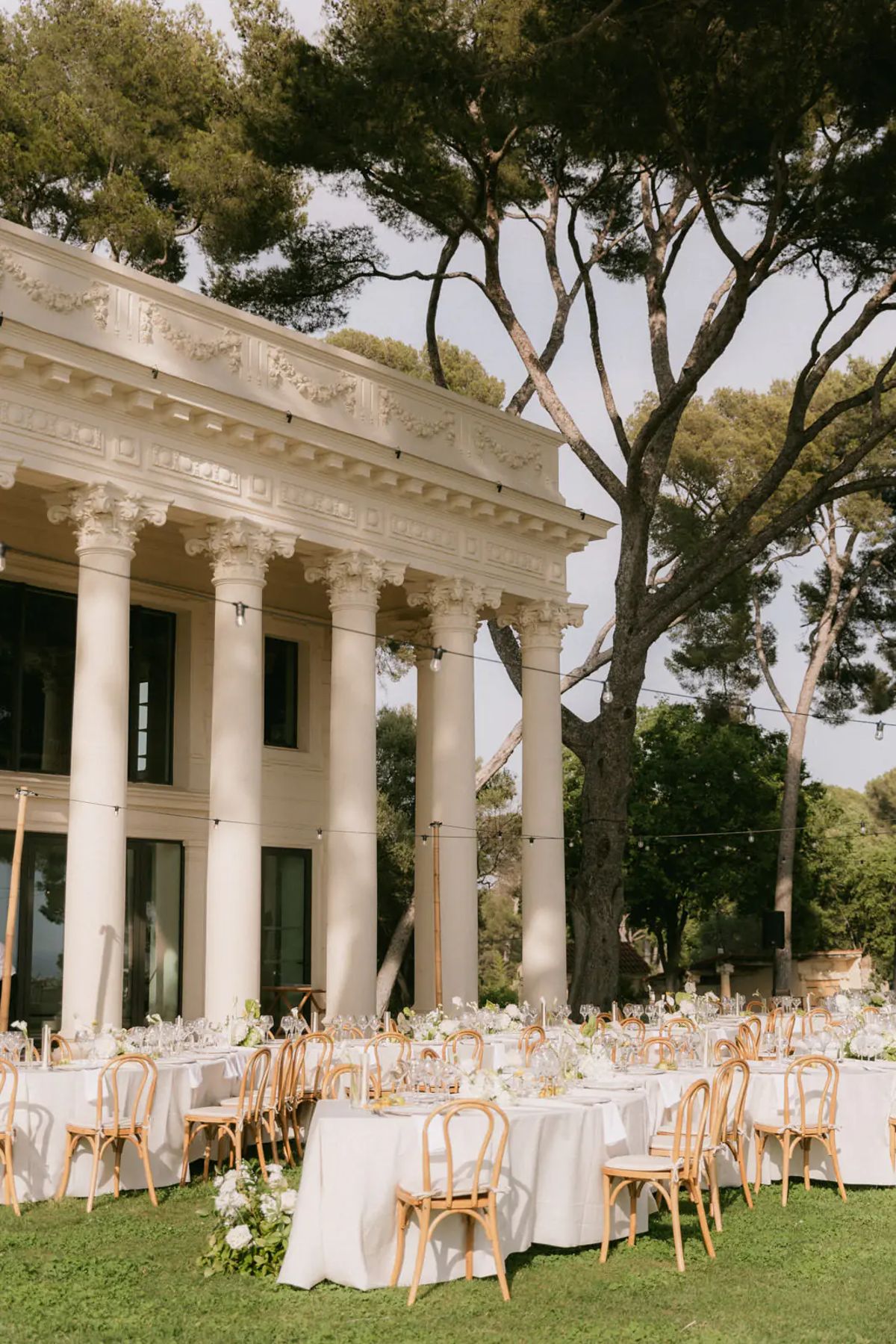 Guests dressed in white at a poolside party under pine trees at Domaine Rocabella, French Riviera