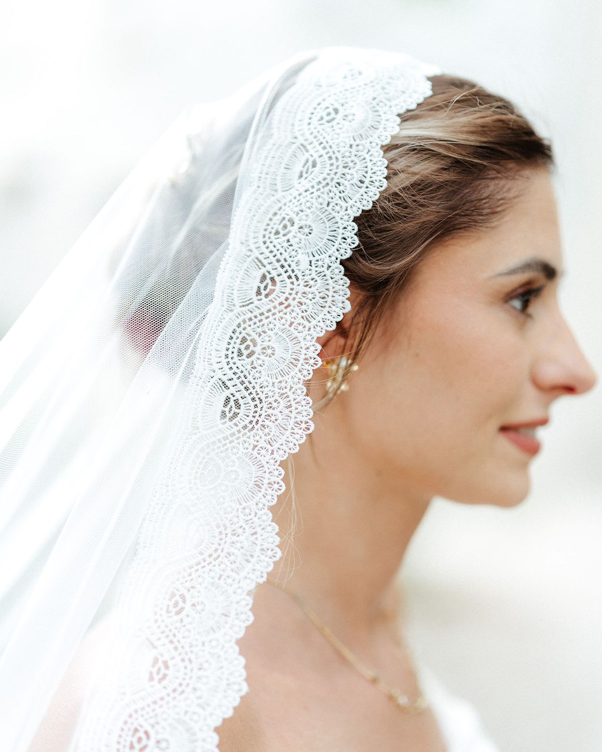 Profile of the bride wearing a lace edged veil over her hair