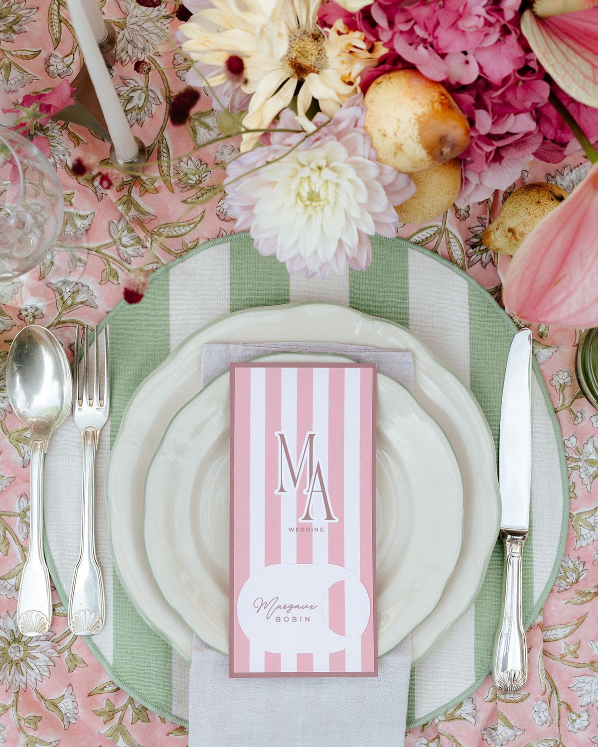 Overhead place setting with a green striped napkin, silver cutlery and a pink striped menu card