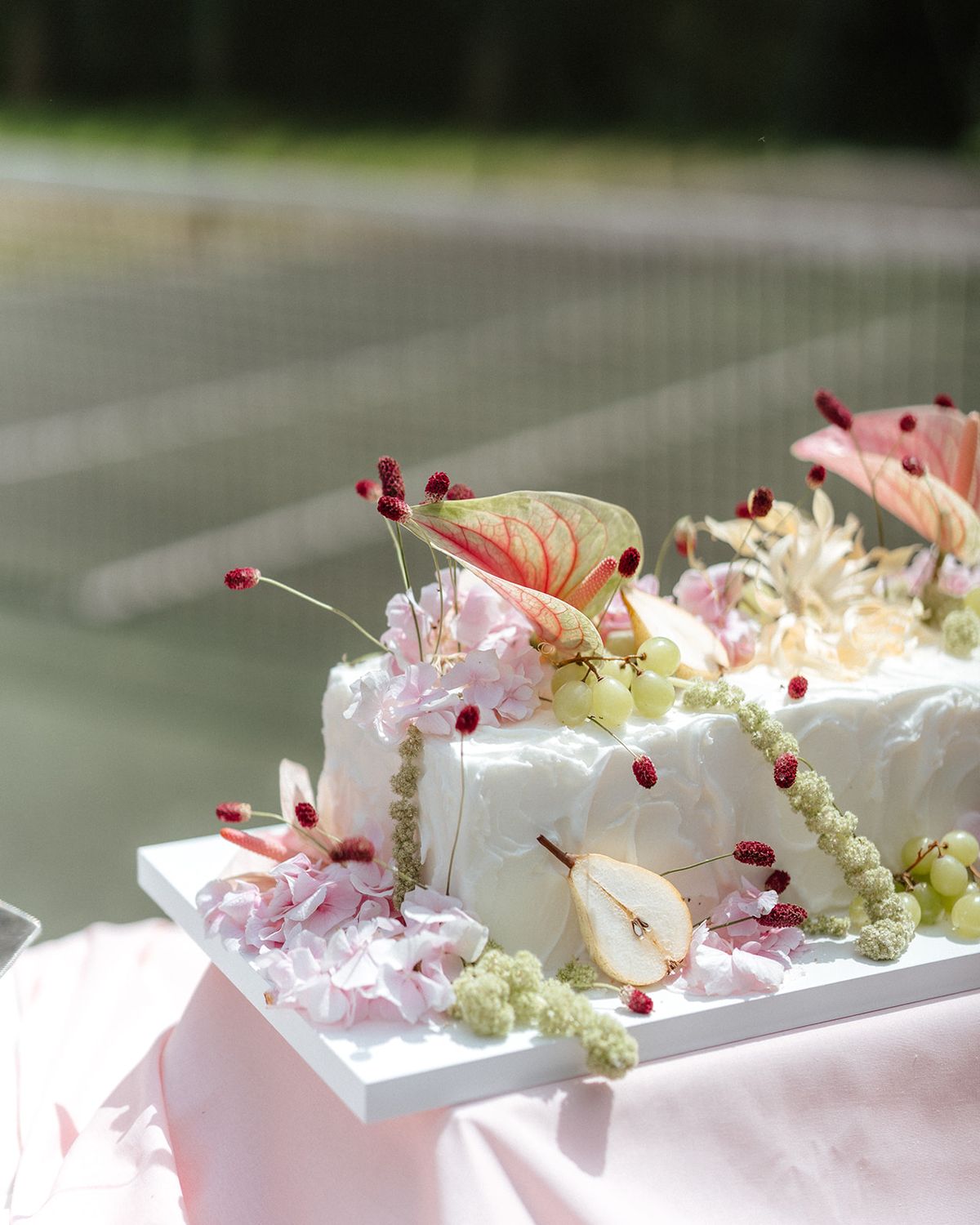 White cake topped with anthurium, pear slices and red berries