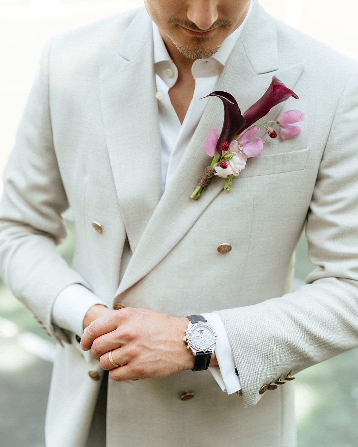 Groom in a cream double-breasted linen suit with a burgundy calla and sweet pea boutonniere