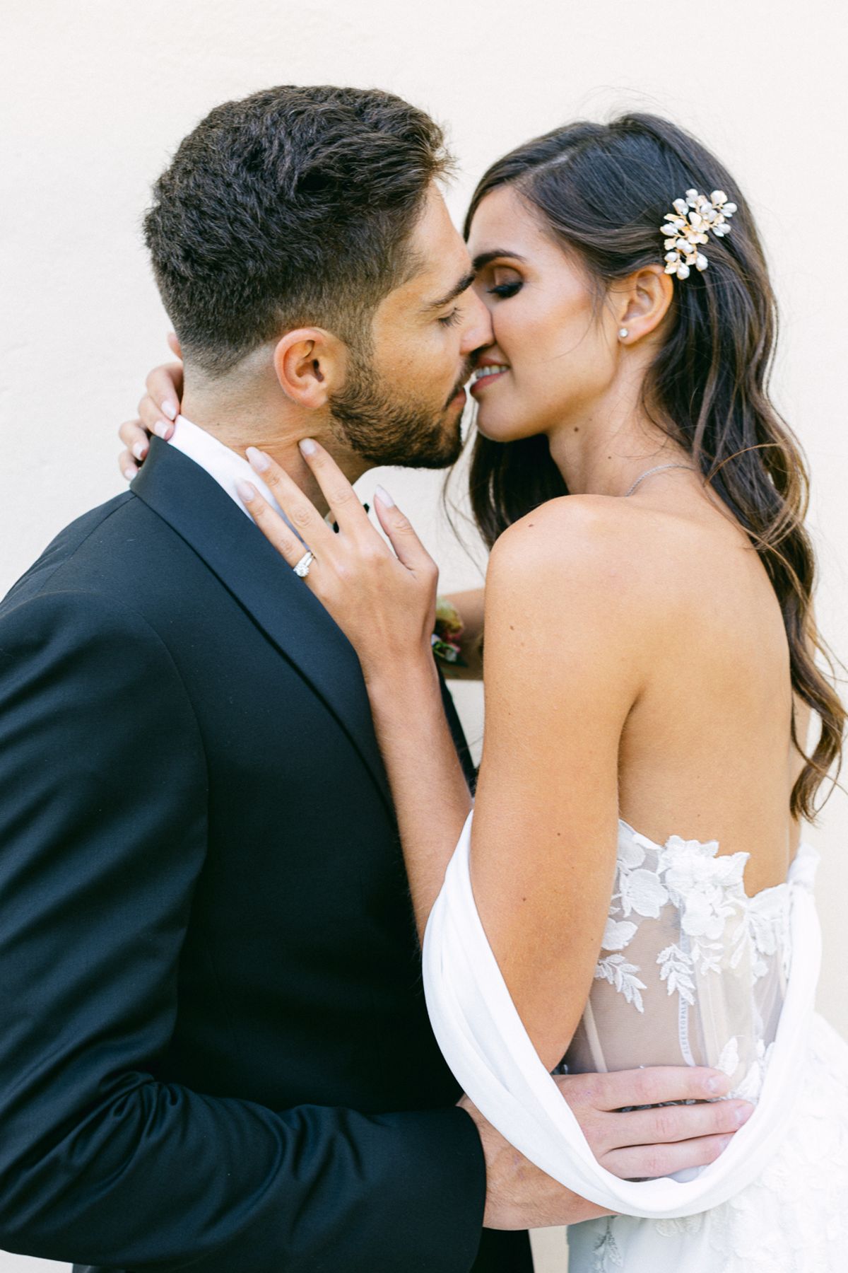 A close portrait of the couple kissing, the groom in a dark suit and the bride in a strapless gown with a hair clip.