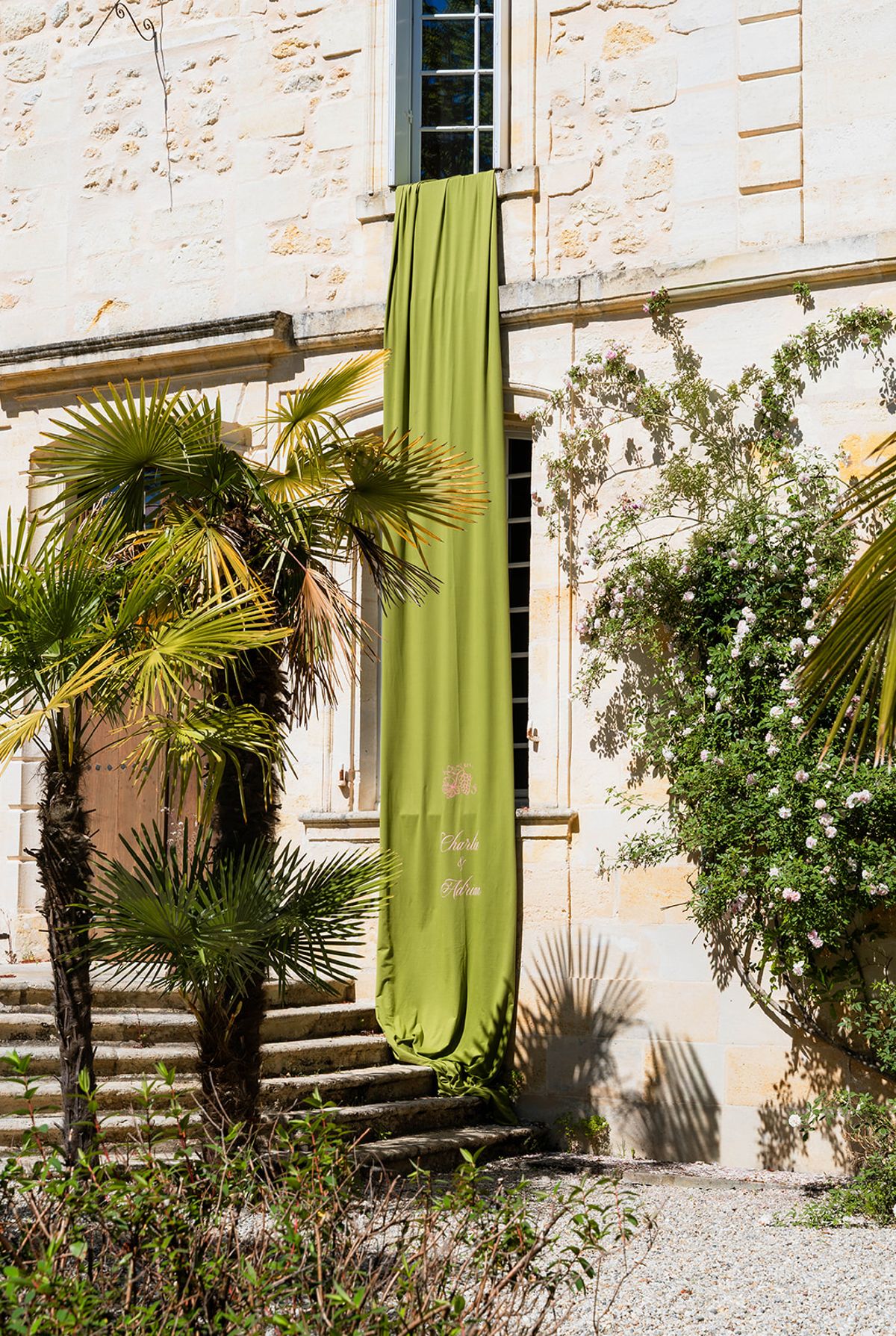A chartreuse velvet banner hung from a window down the chateau's limestone facade beside climbing roses