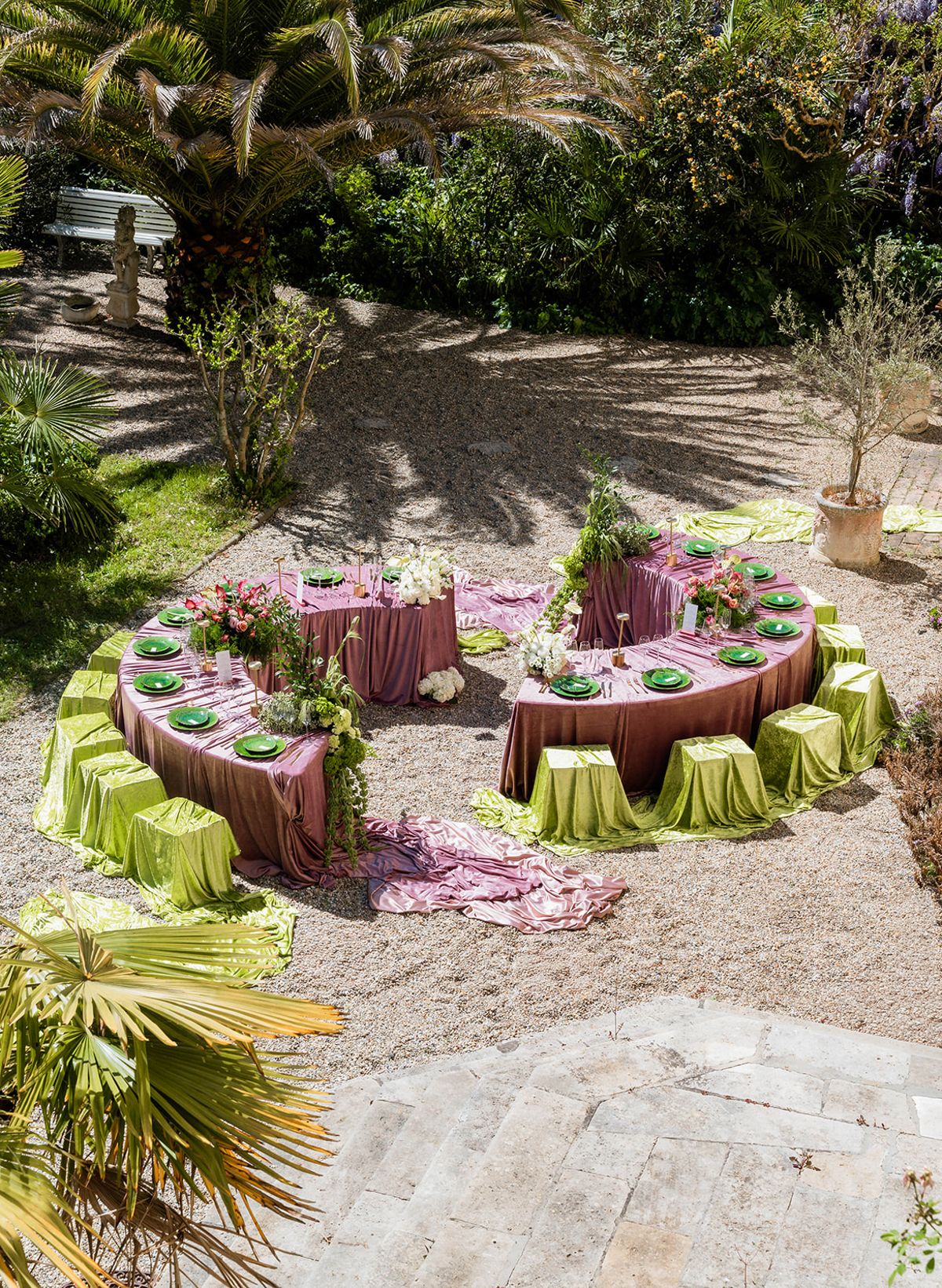 Raised view of the two crescent tables dressed in mauve velvet with chartreuse stools and abundant florals