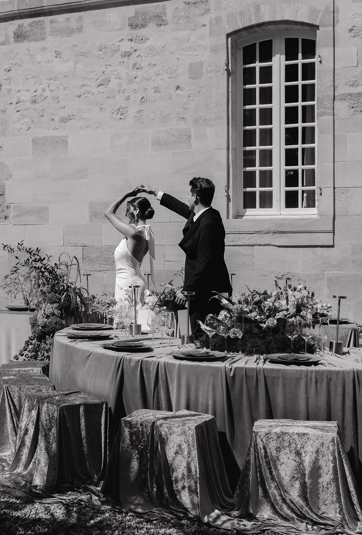Black and white portrait of a couple beside the velvet-draped crescent table