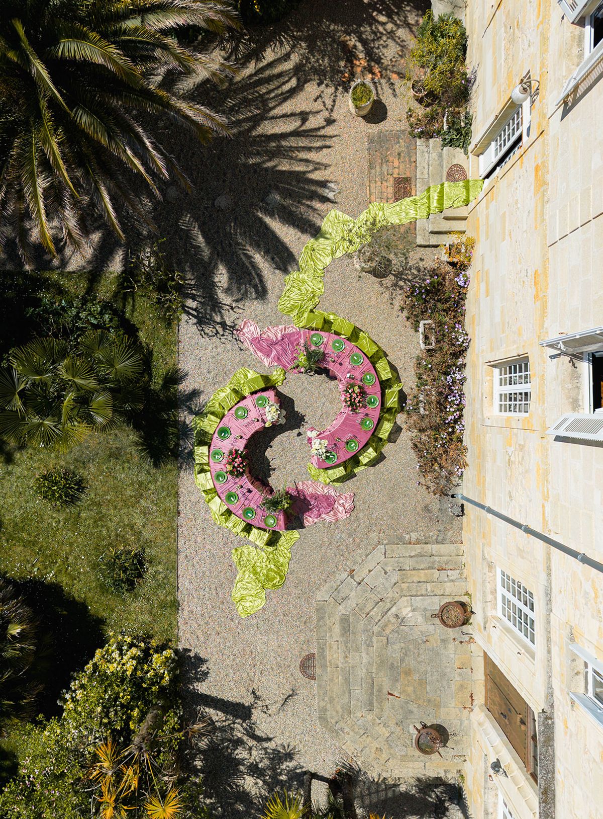 Aerial view of the crescent reception tables set on gravel among palms in the chateau grounds