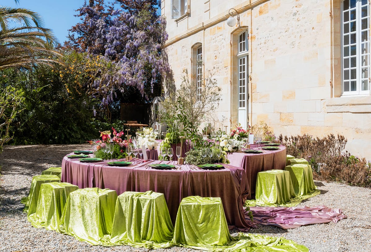 The dressed crescent table with wisteria and the chateau facade behind in spring sunlight
