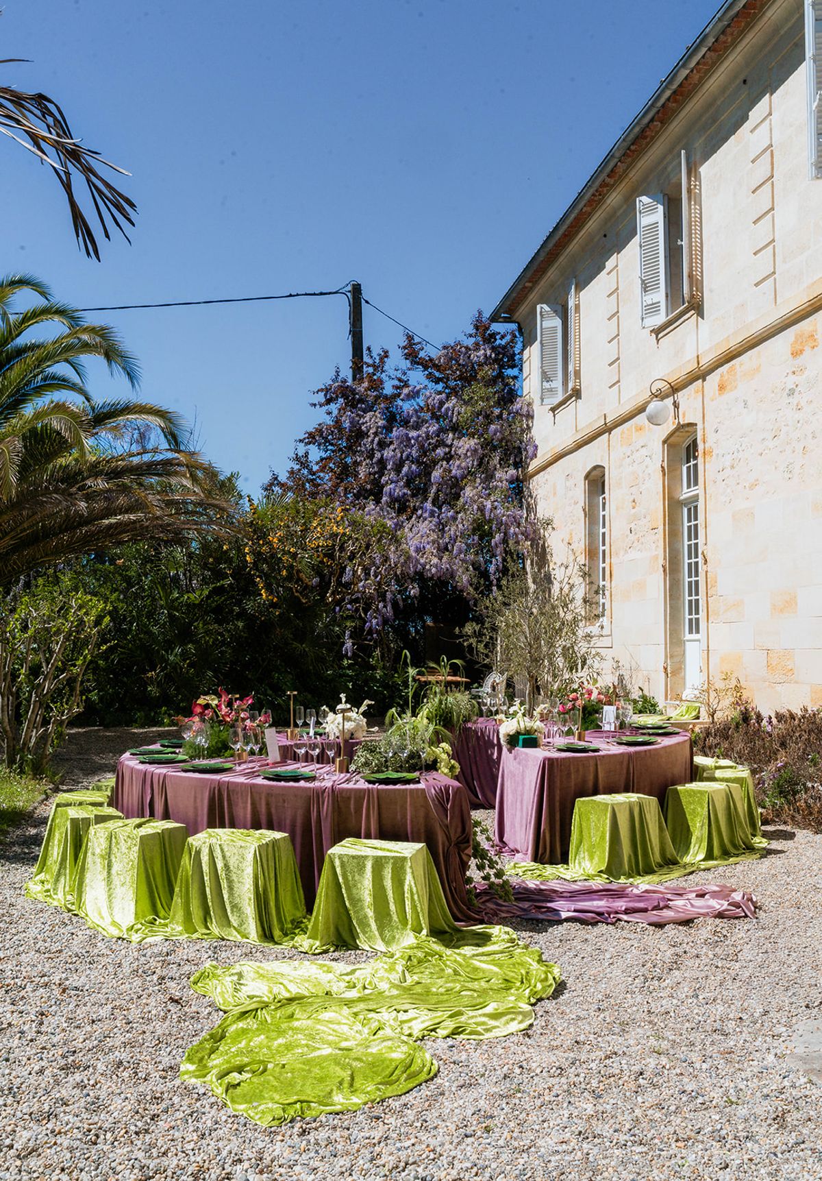 The chateau's limestone facade with wisteria in bloom above the dressed reception tables
