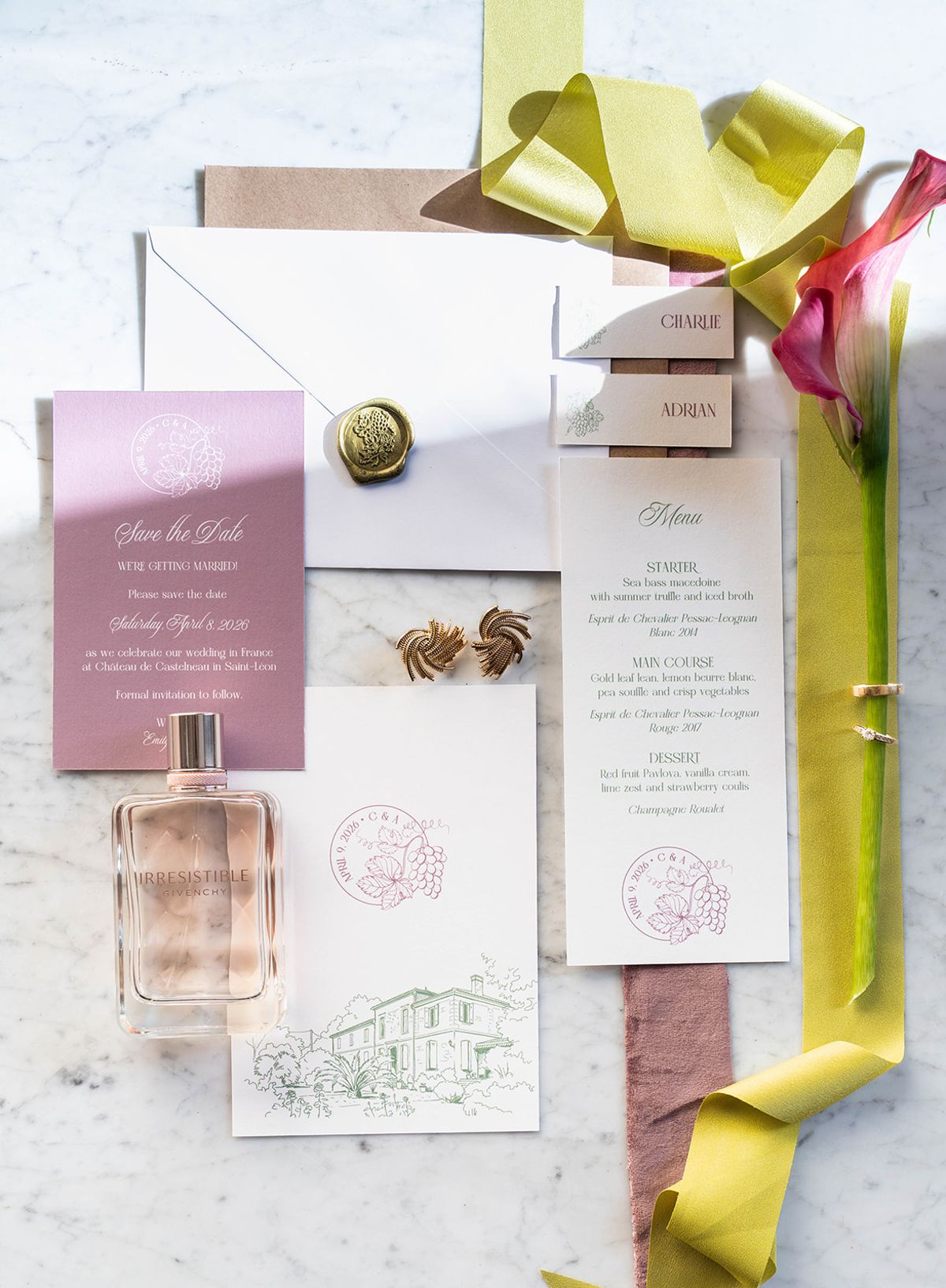Flat lay of the stationery suite with chartreuse ribbon, menu cards and perfume on marble