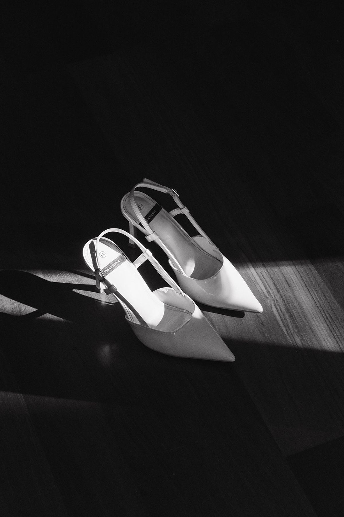 Black and white still life of bridal shoes in directional light