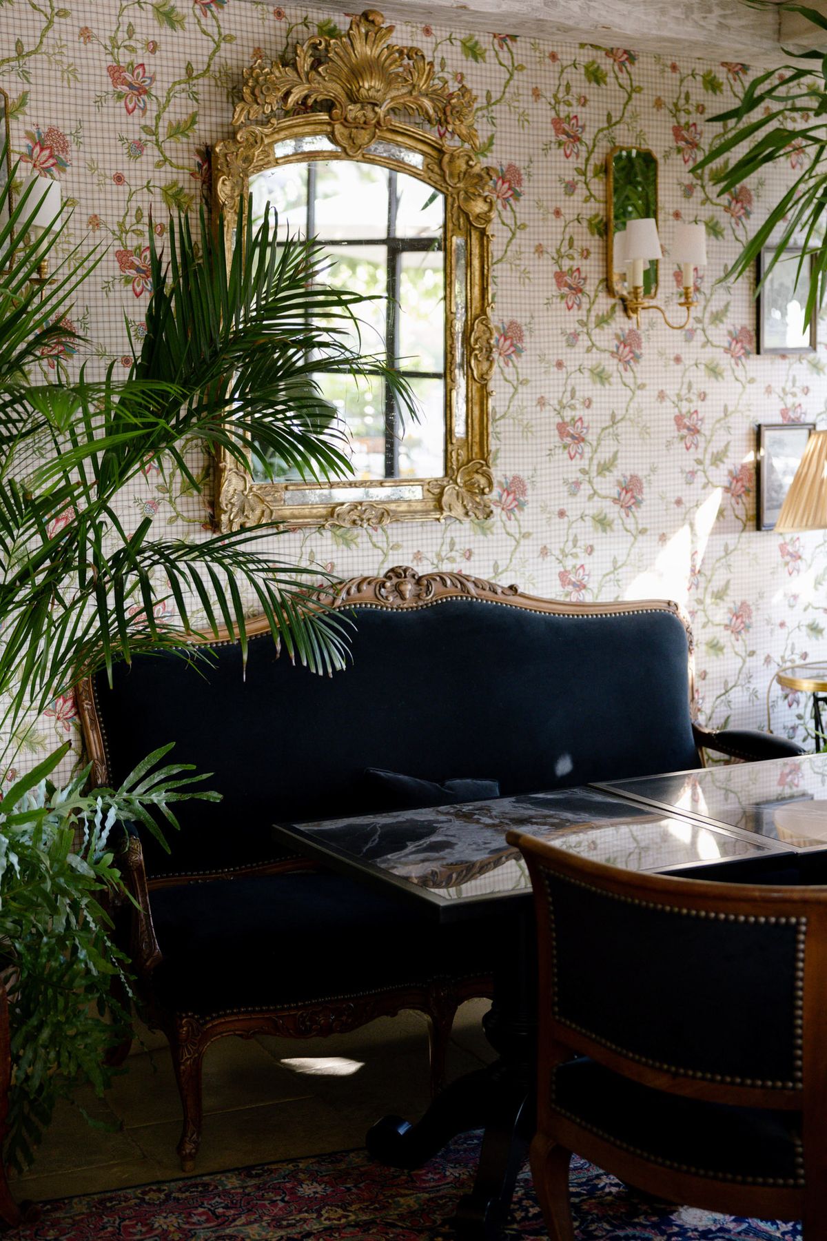 Hotel salon with floral wallpaper and a gilt mirror