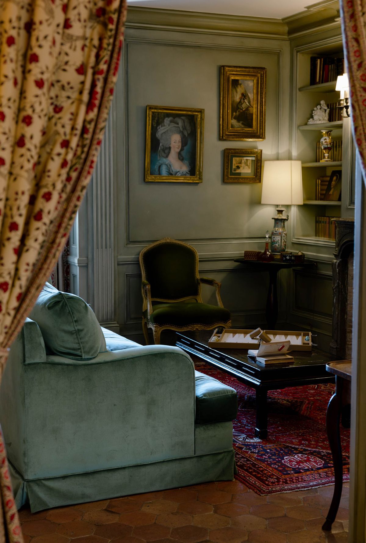 Hotel sitting room with portraits and a green sofa