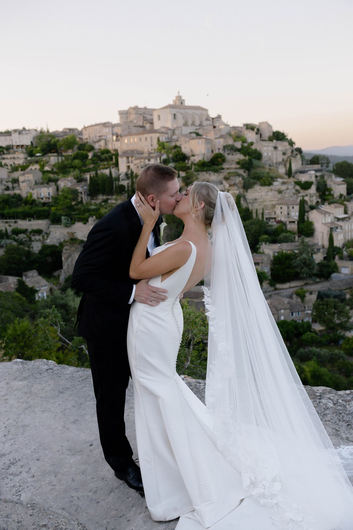Kirstin and Ryan kissing with Gordes behind at dusk