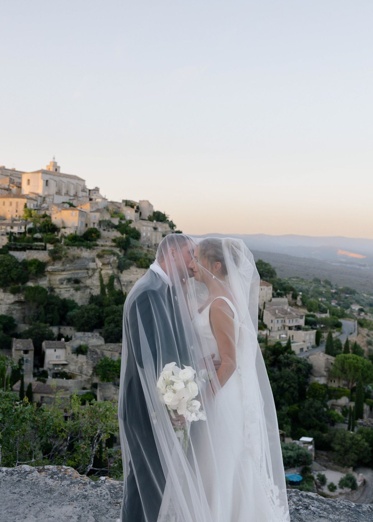 Kirstin and Ryan kissing under her veil with Gordes behind