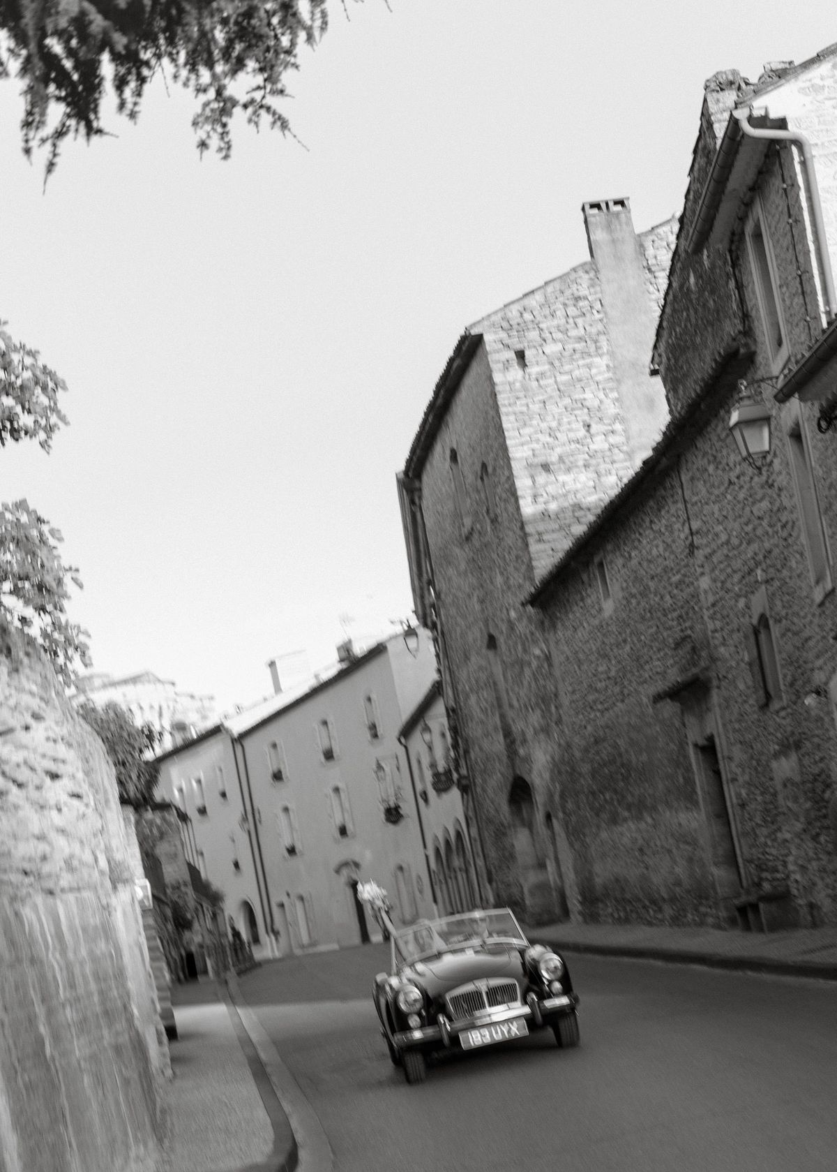 Black and white photo of a convertible driving through the village