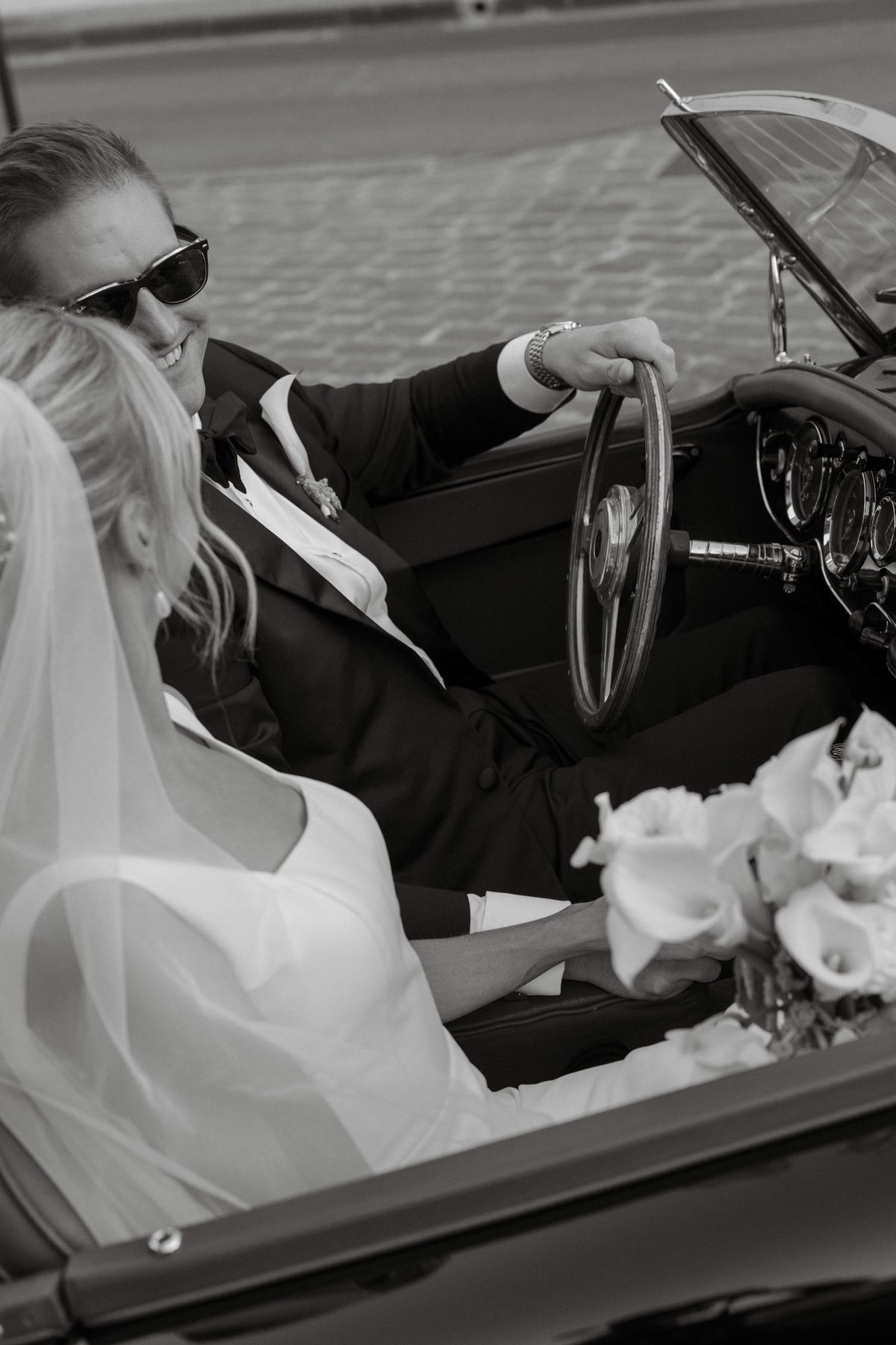 Black and white photo of the couple driving in a convertible