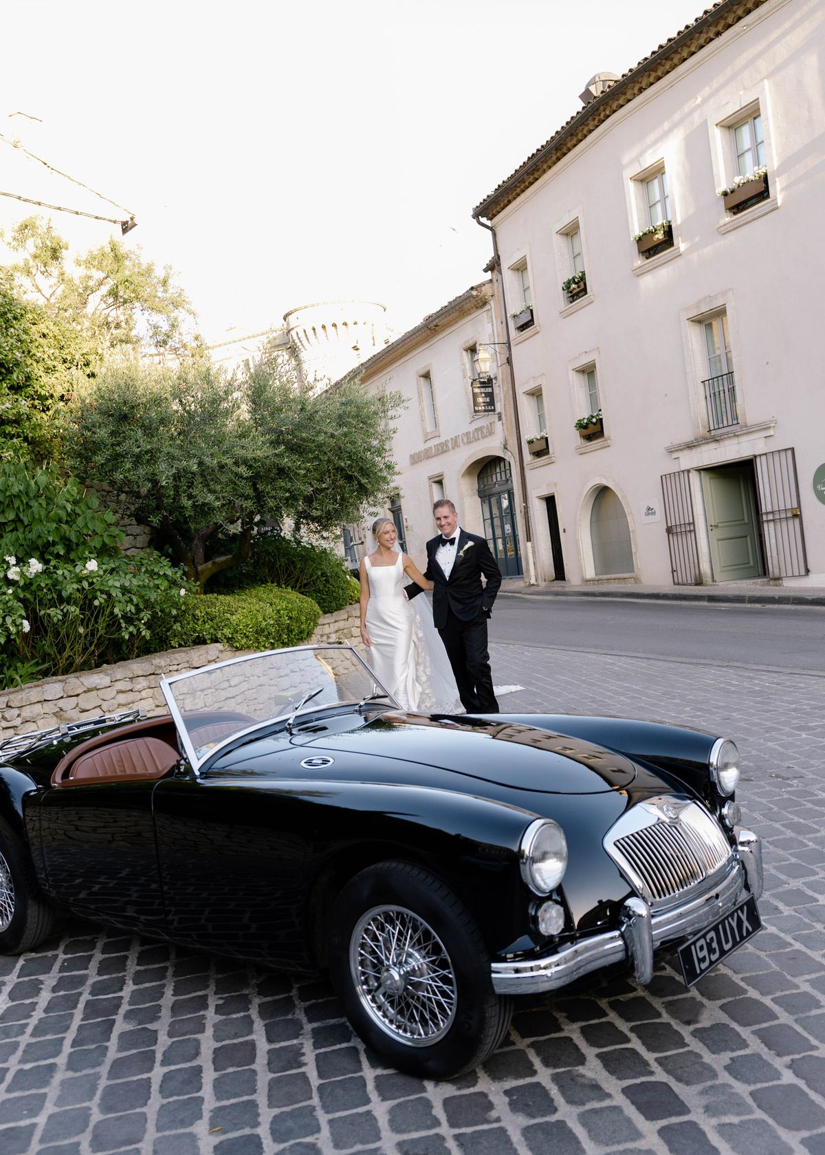 Kirstin and Ryan beside a black vintage convertible in the village street