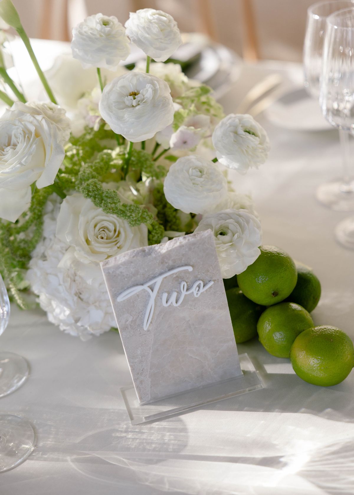 White ranunculus centrepiece with limes and a table number