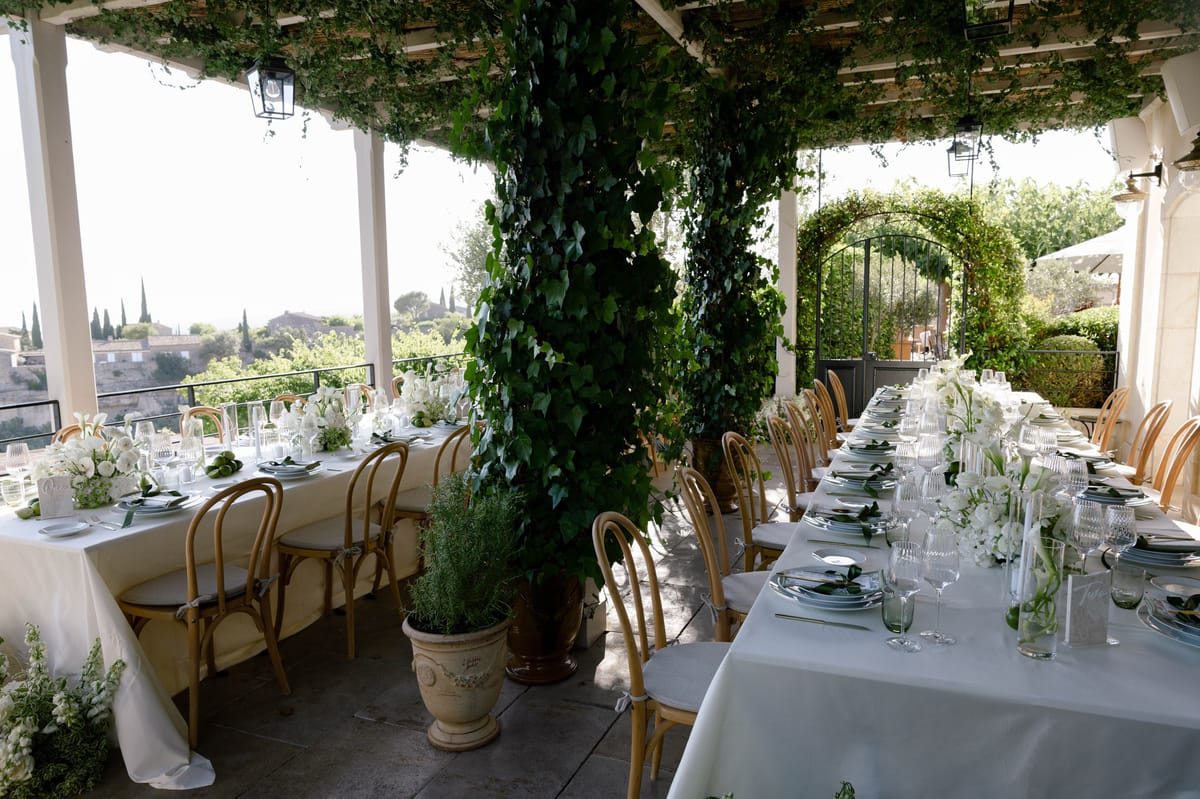 Long dinner table beneath a vine-covered pergola