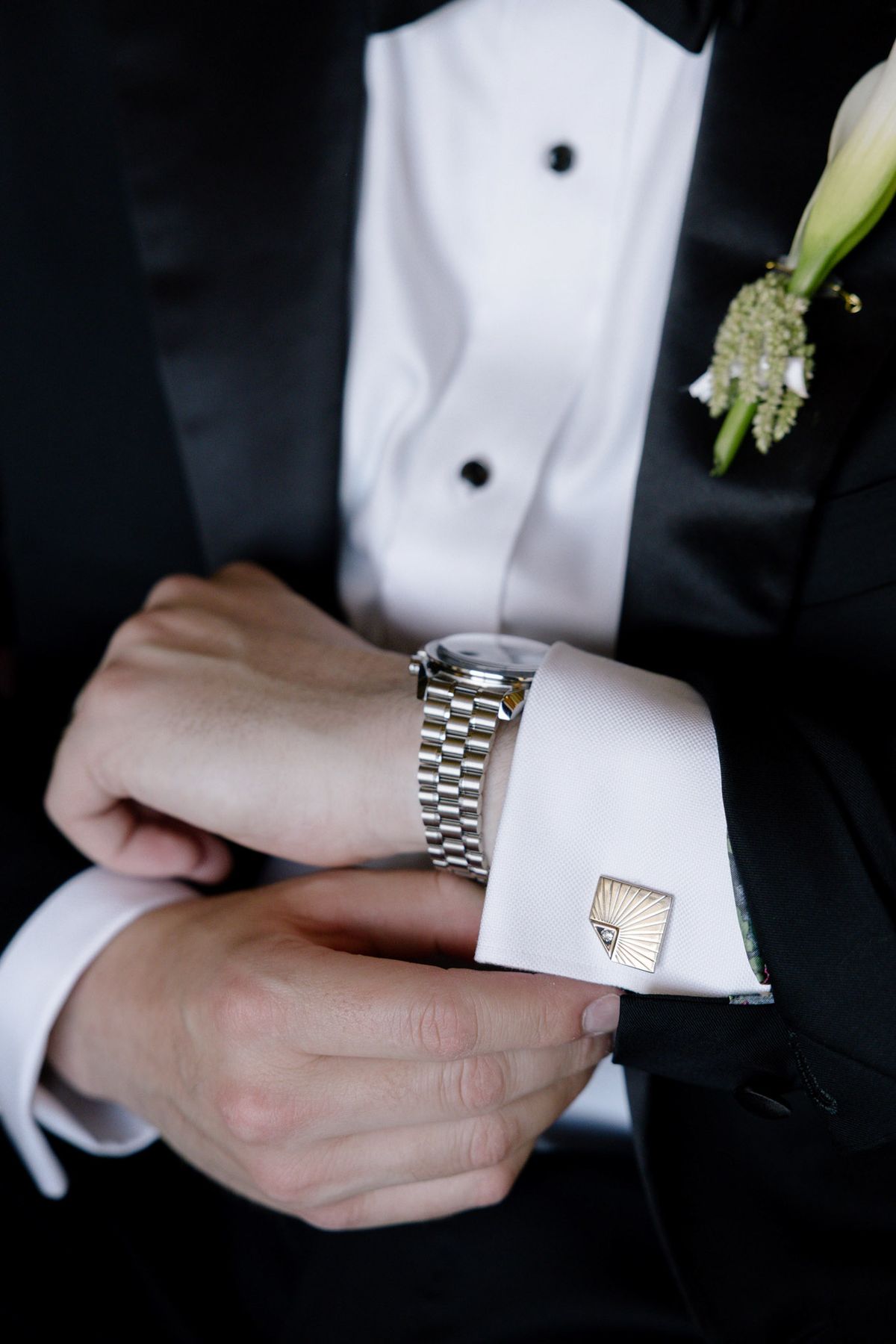 Groom fastening his watch and cufflink