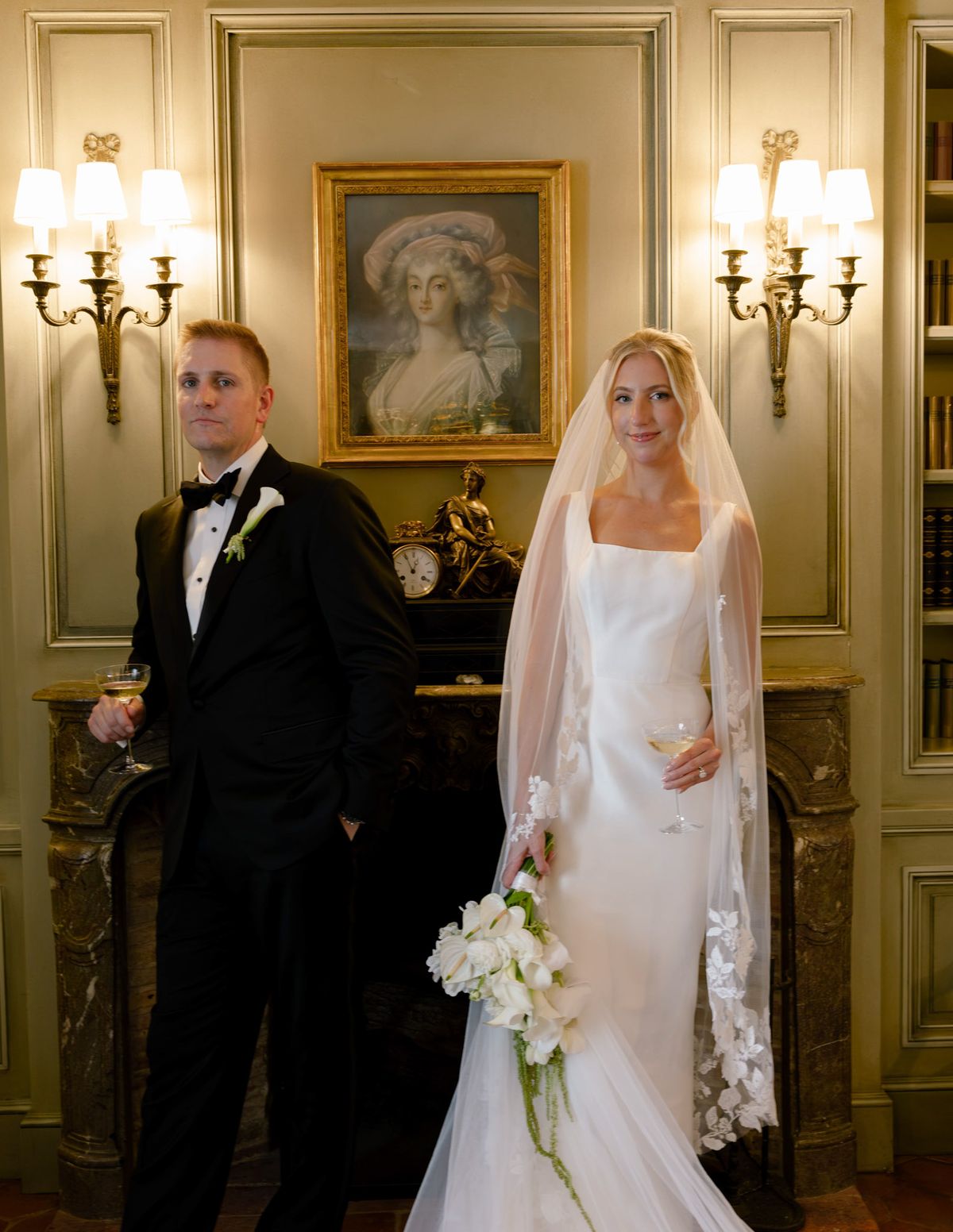 Kirstin and Ryan standing in a panelled library with wall sconces