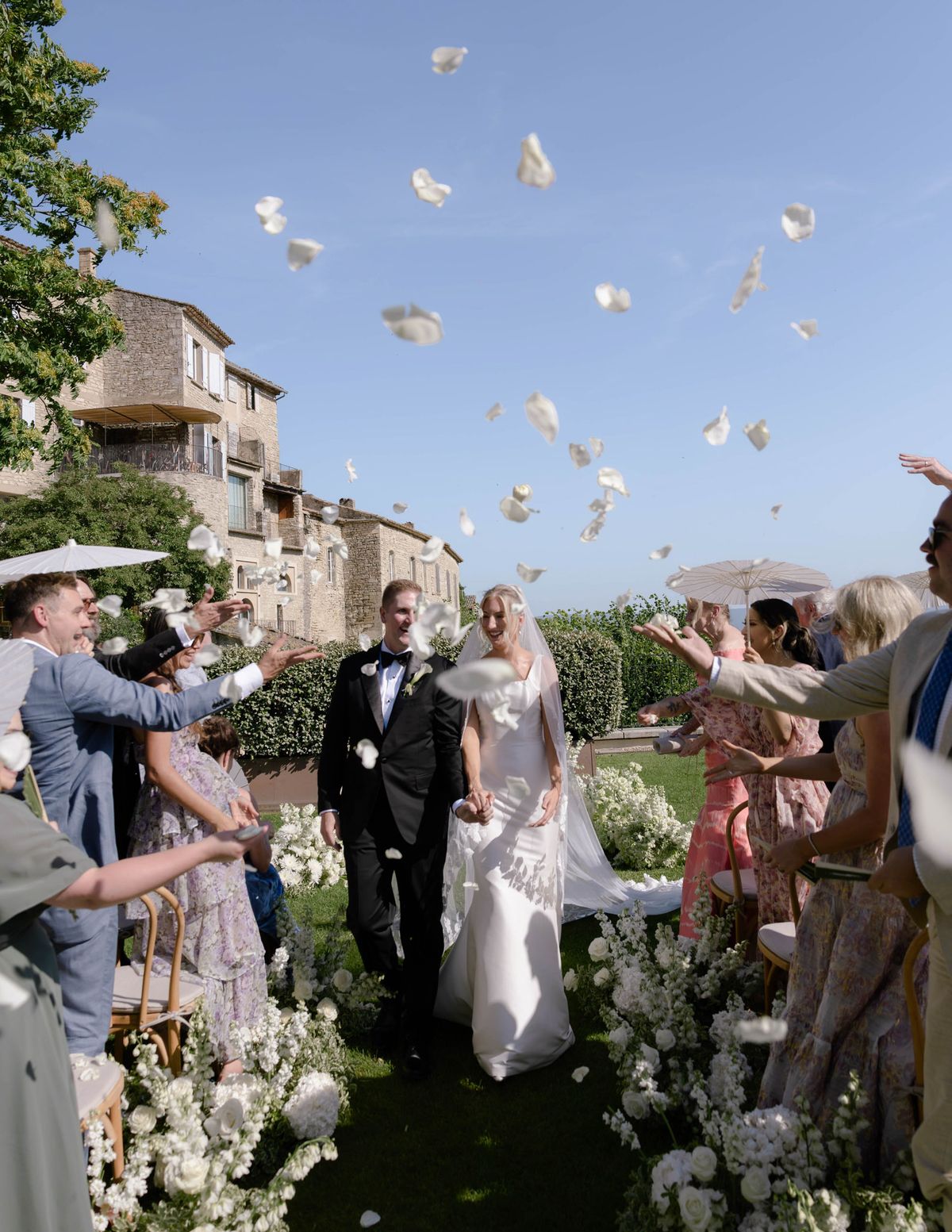 Guests throwing white petals as the couple walk back up the aisle