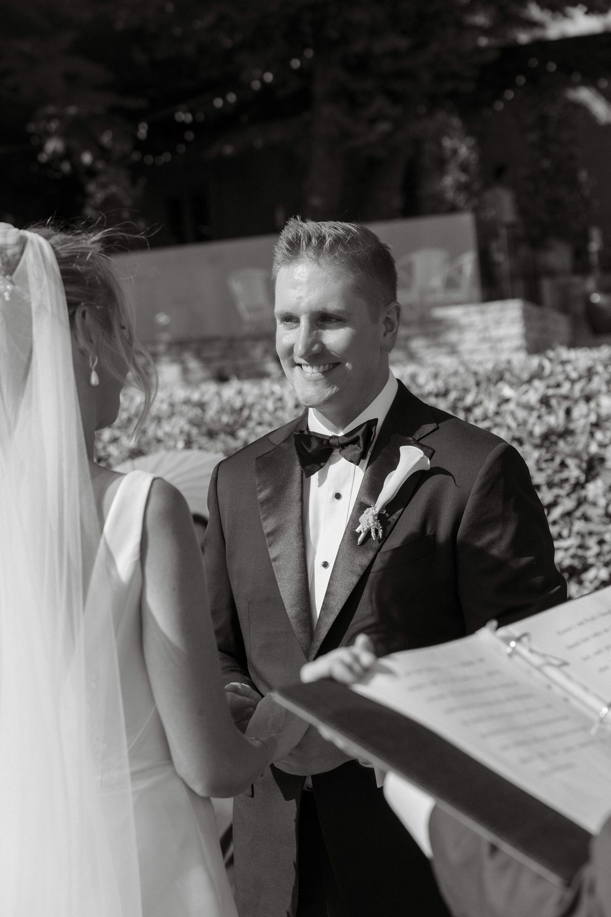 Black and white photo of the groom smiling at the bride