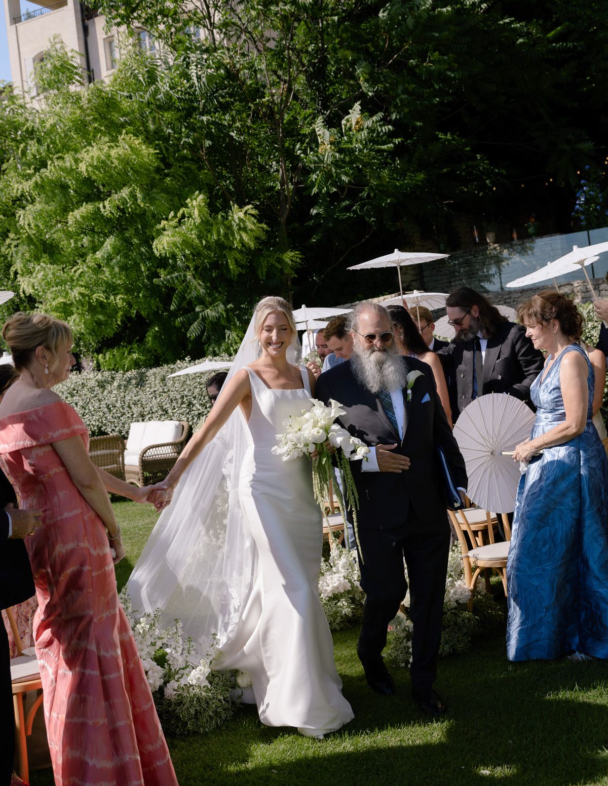 Bride on her father's arm in the aisle with guests standing