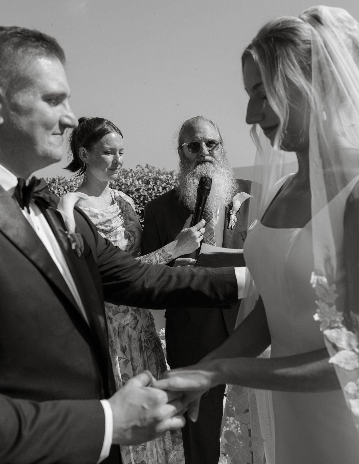 Black and white photo of the bride's father officiating as the couple hold hands