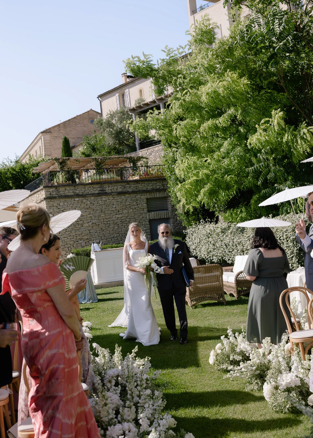 Bride and her father coming down the aisle past seated guests