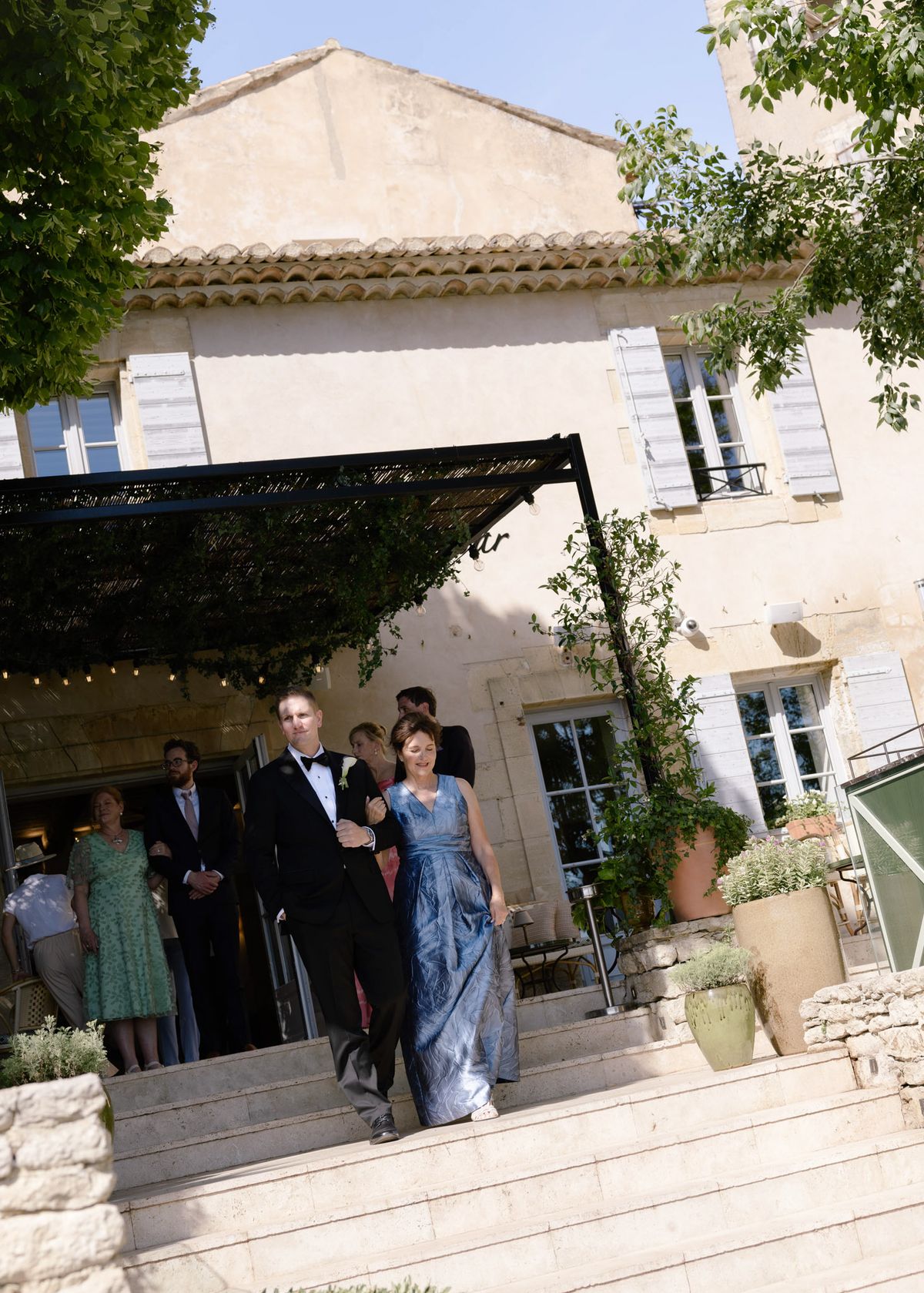 Groom walking down the steps to the ceremony beside a guest in blue