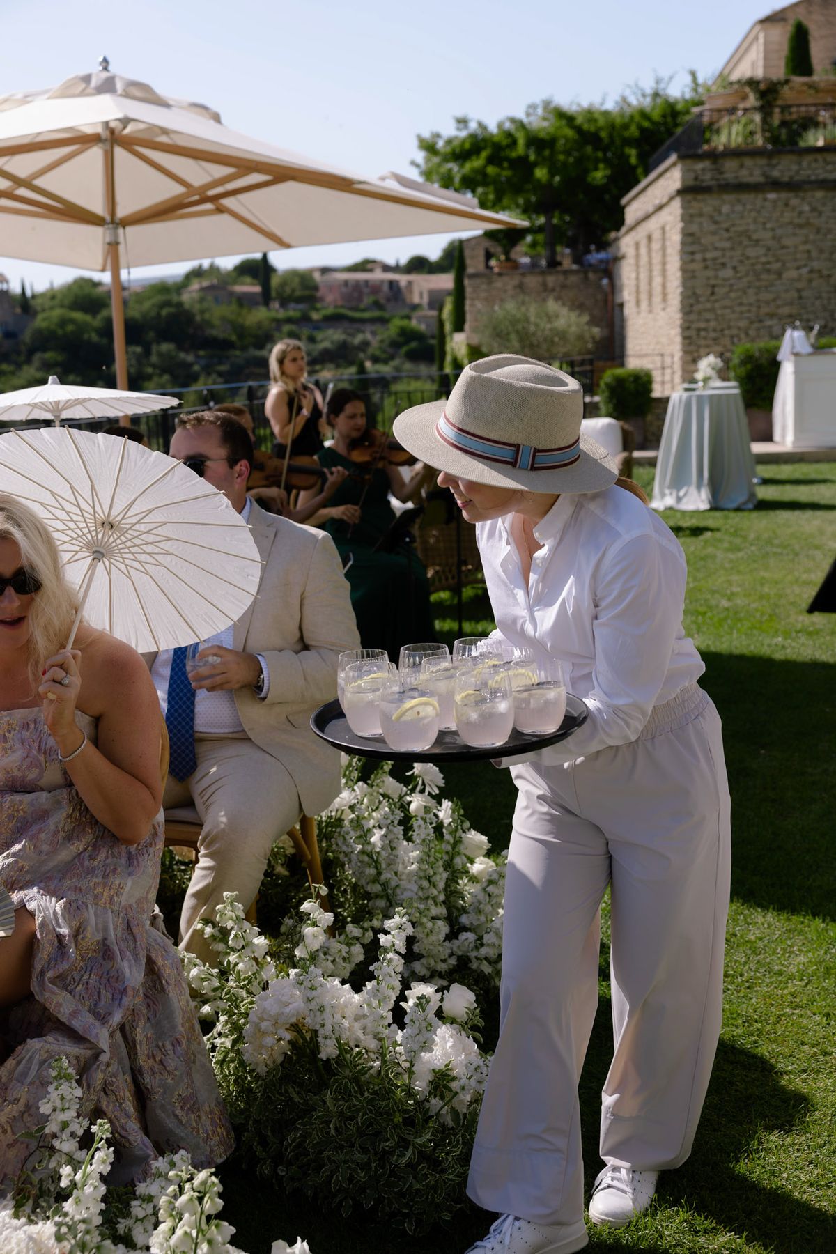 Waiter serving drinks to guests holding parasols