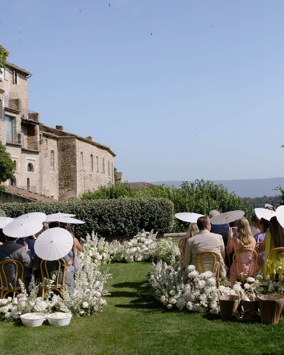 Guests seated with white parasols before the ceremony