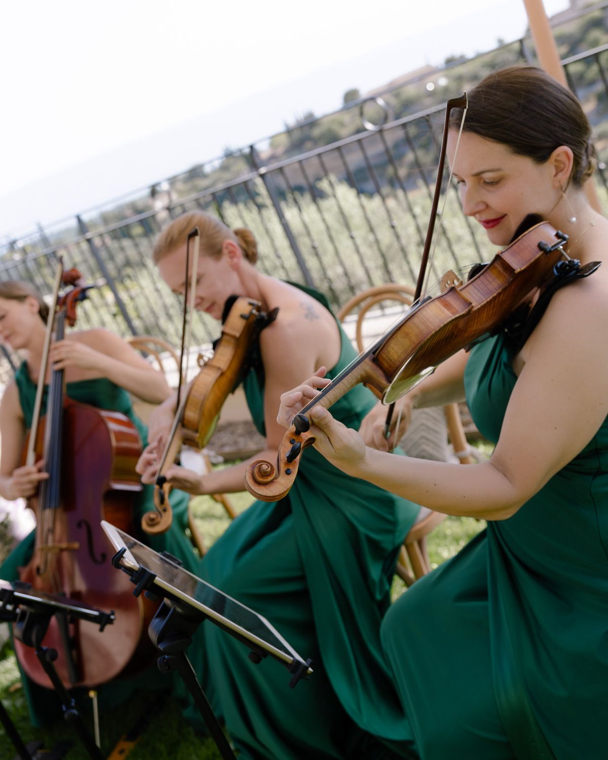 String trio in green dresses playing on the ceremony lawn