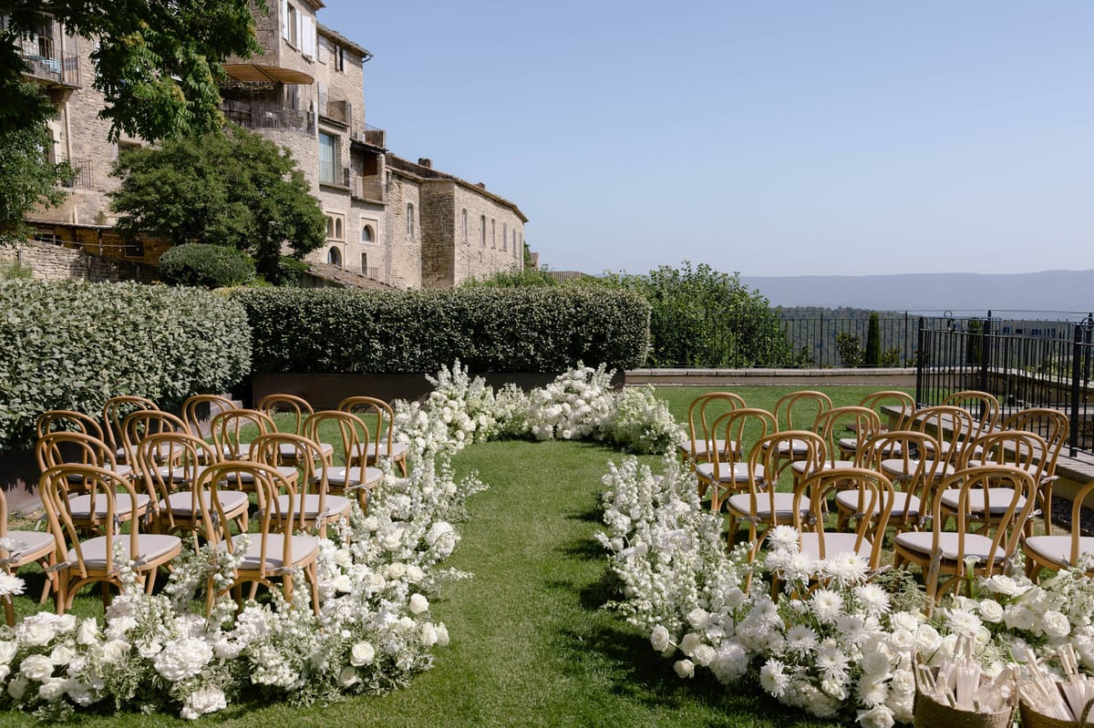 Empty ceremony aisle lined with white flowers on the lawn beneath the hotel