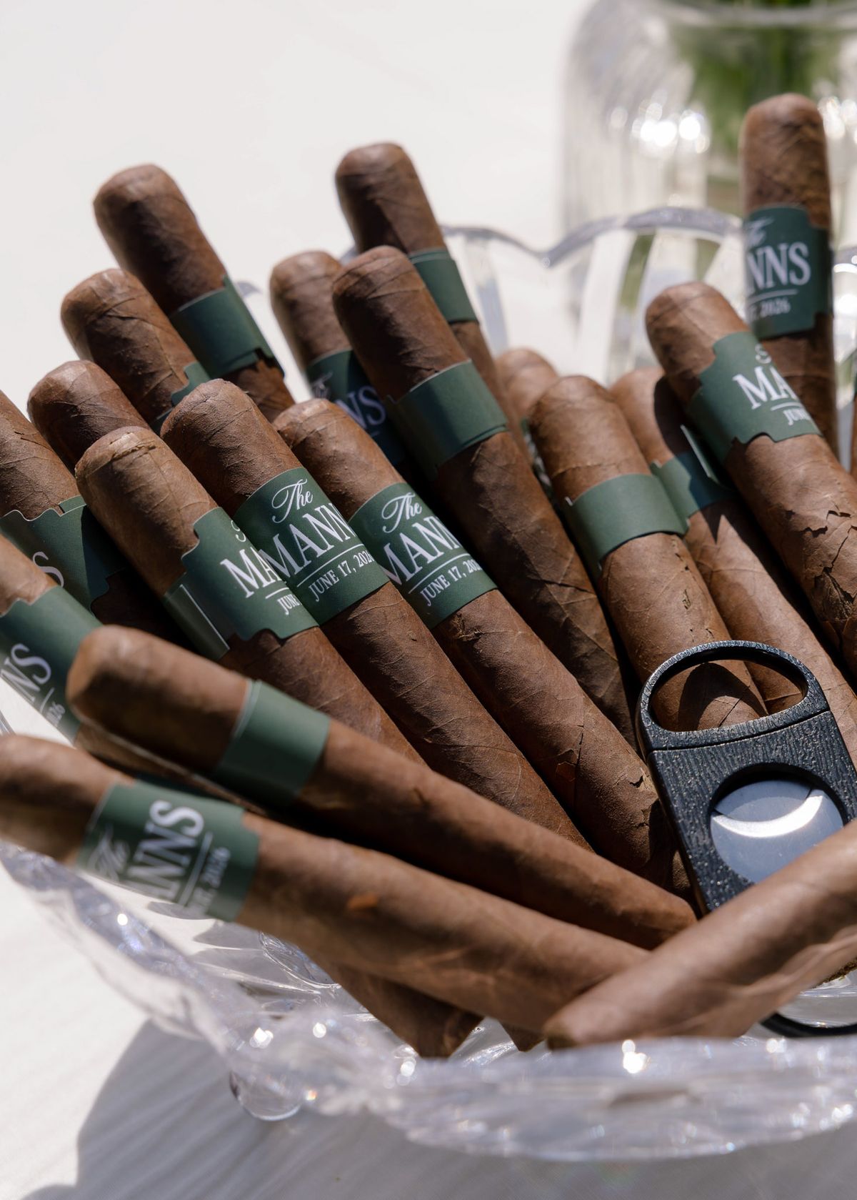 Custom-banded cigars in a glass bowl with a cutter