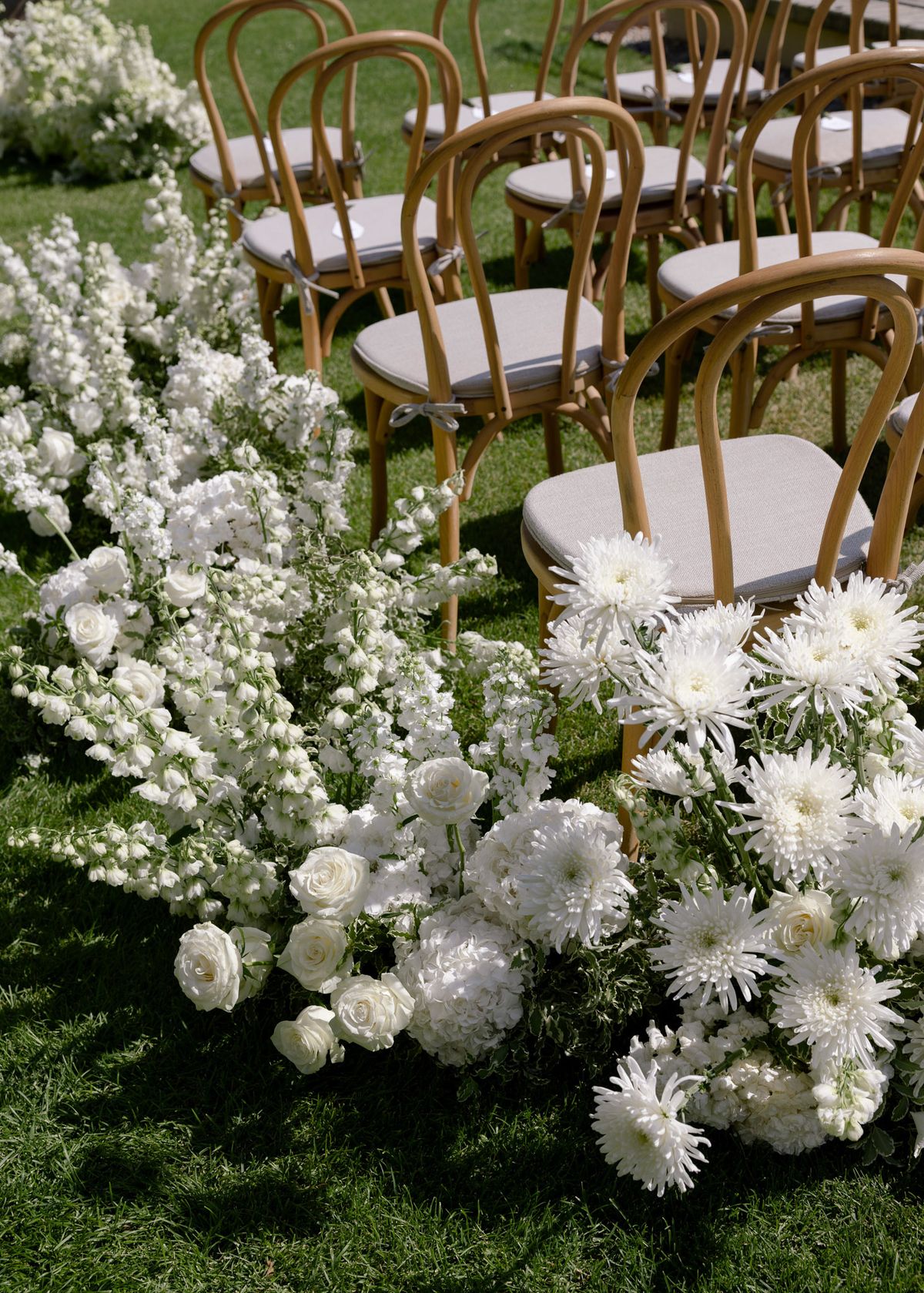Bentwood chairs and white flowers along the ceremony aisle