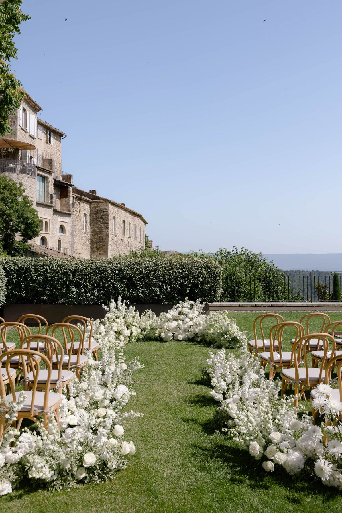 Ceremony aisle lined with white flowers on a terrace lawn