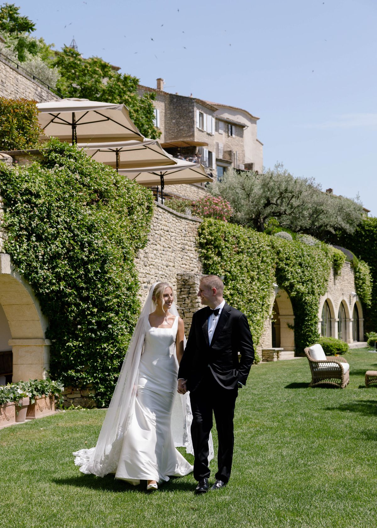 Kirstin and Ryan walking arm in arm across the lawn below the hotel terraces