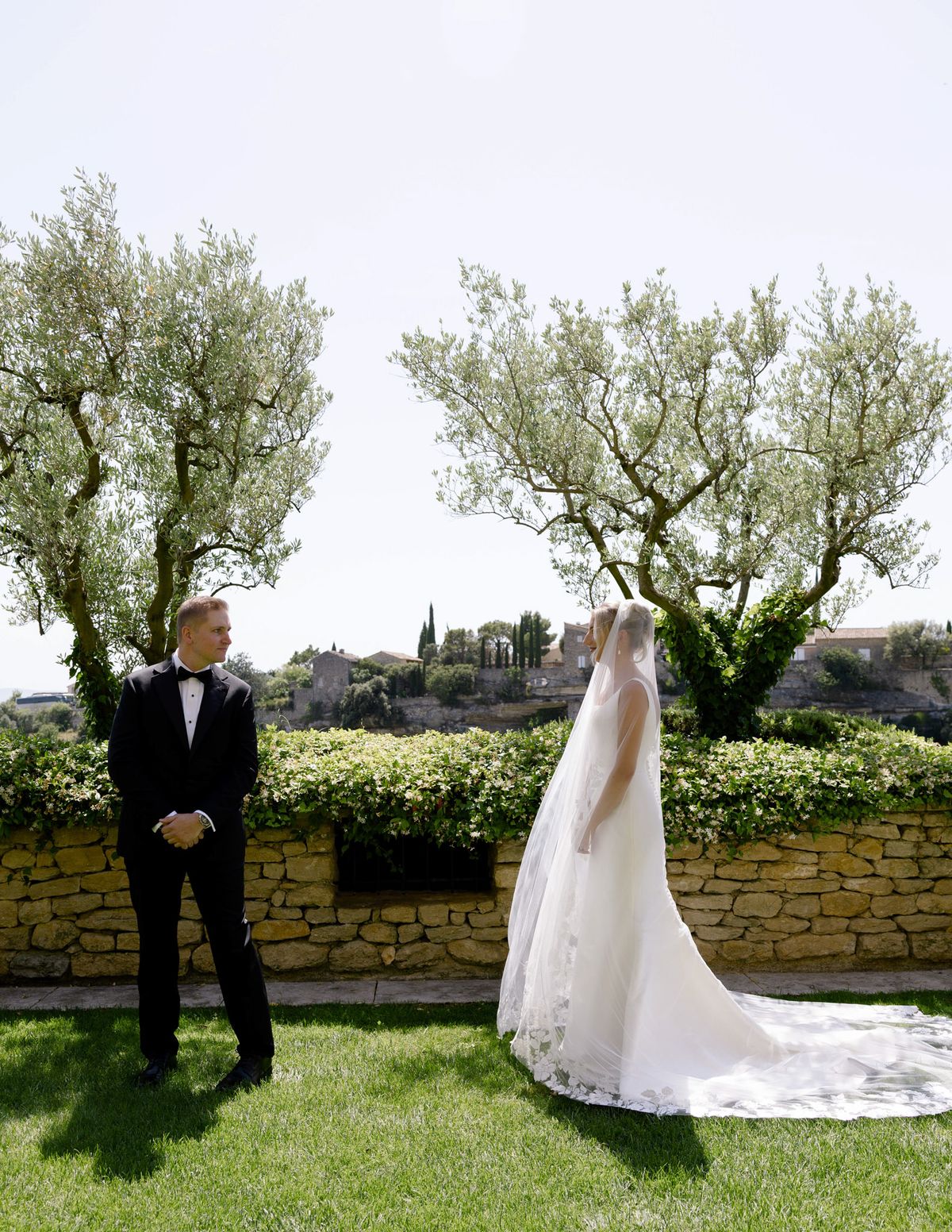 Groom turning to see the bride on the lawn between two olive trees at the first look