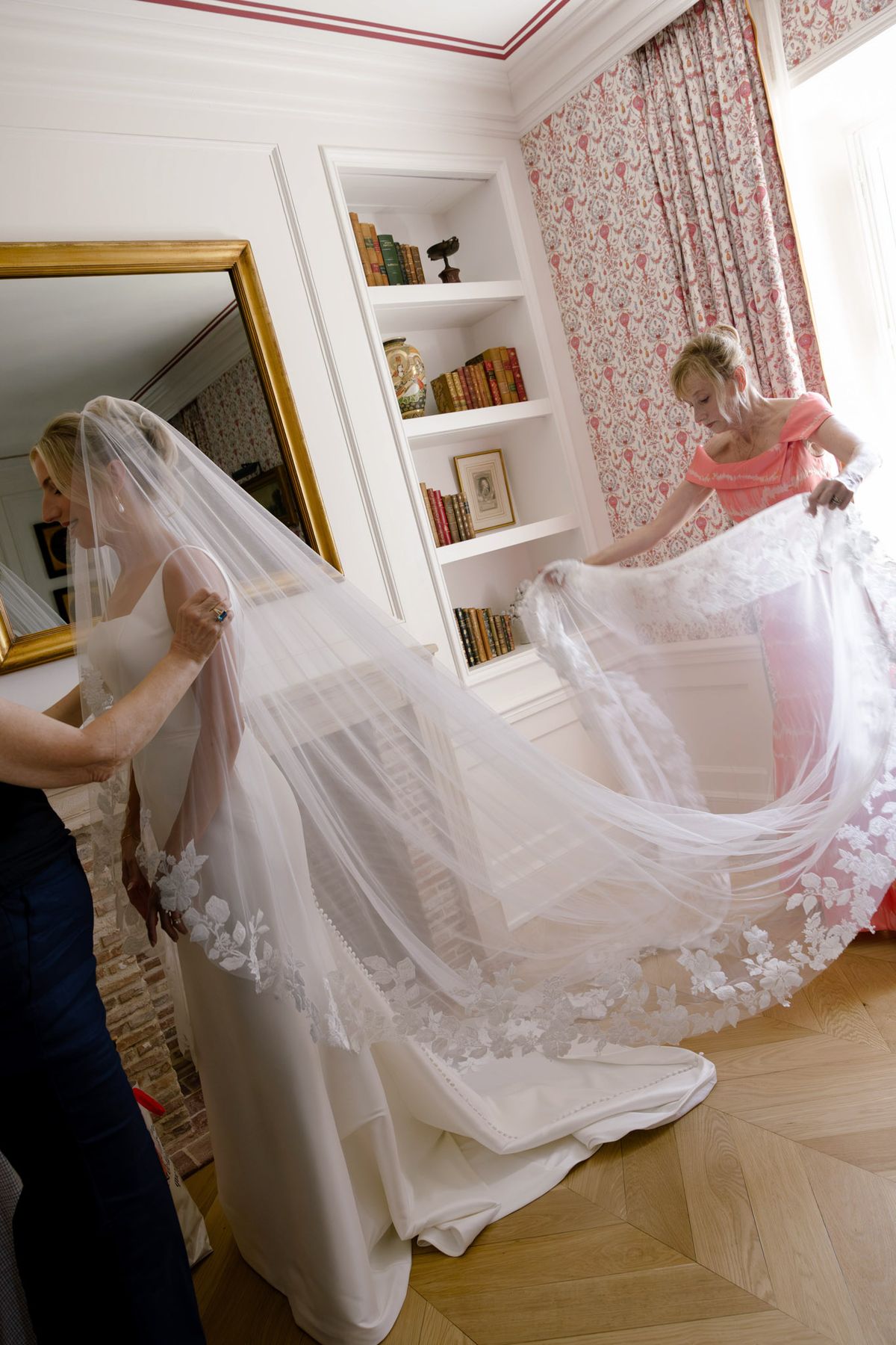 Veil being arranged over the bride's train in a hotel room
