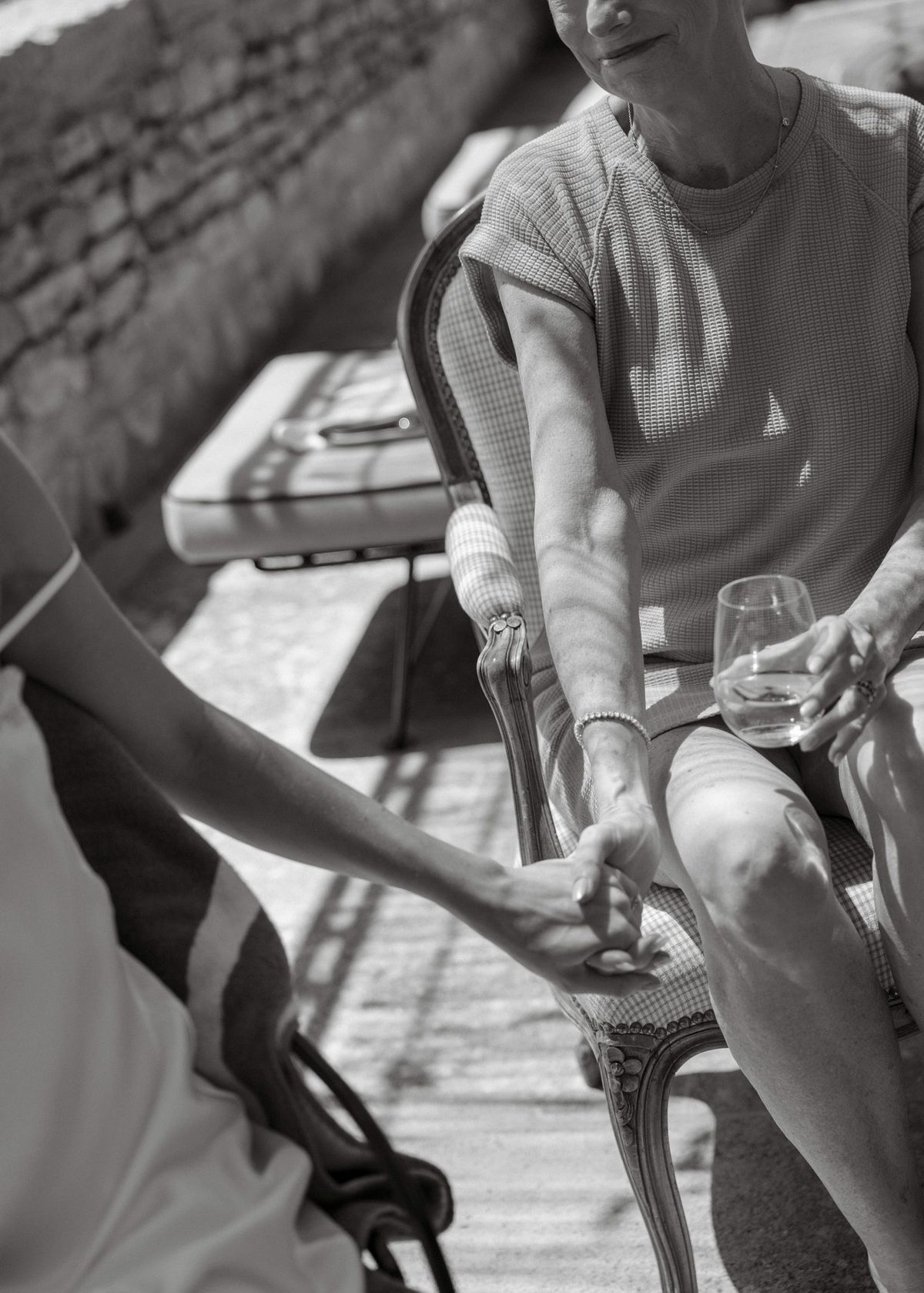 Black and white photo of two women holding hands on a sunny terrace